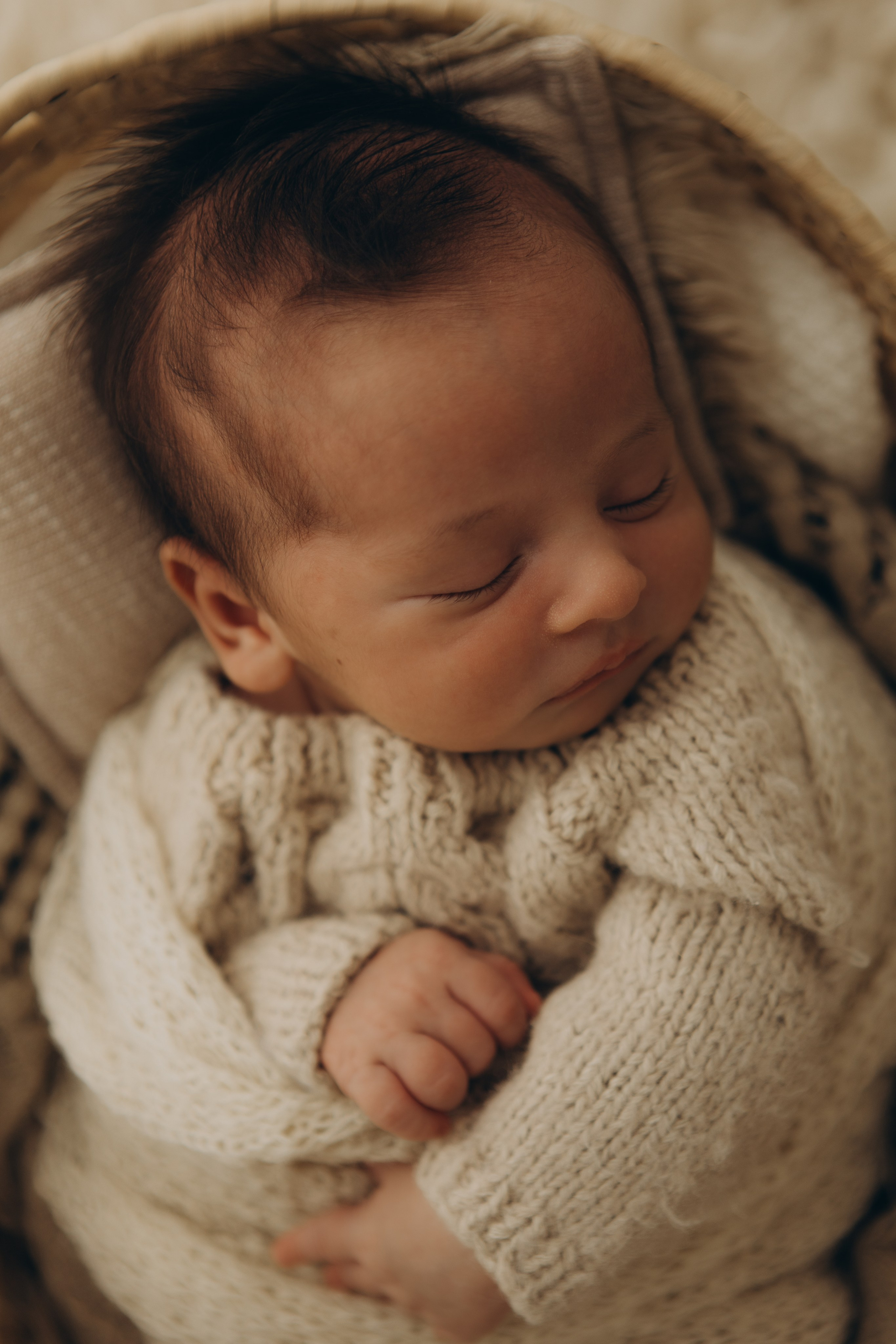 newborn envolto em manta neutra em estúdio com luz natural em Sorocaba