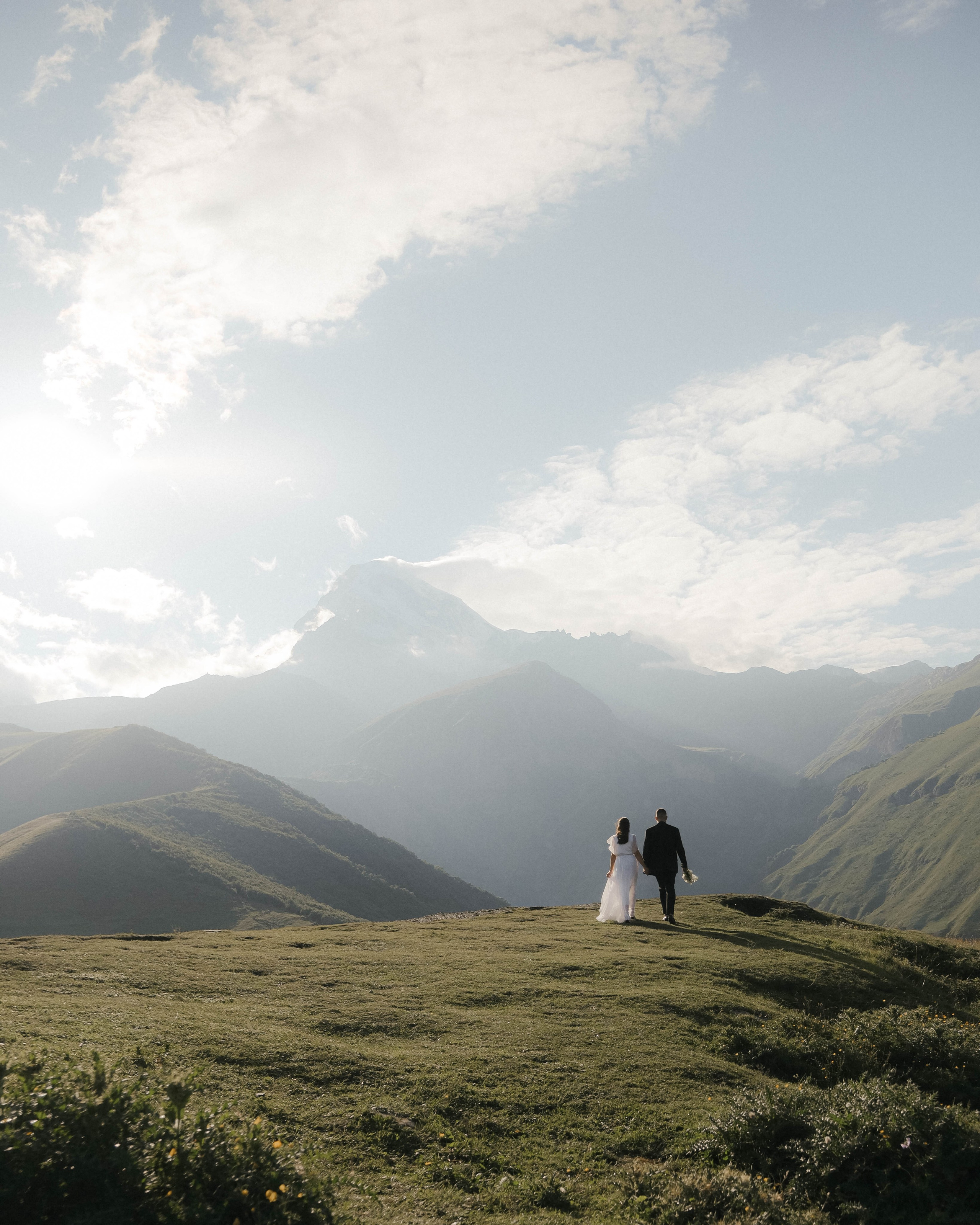 Couple holding hands, golden hour light, Georgian mountains