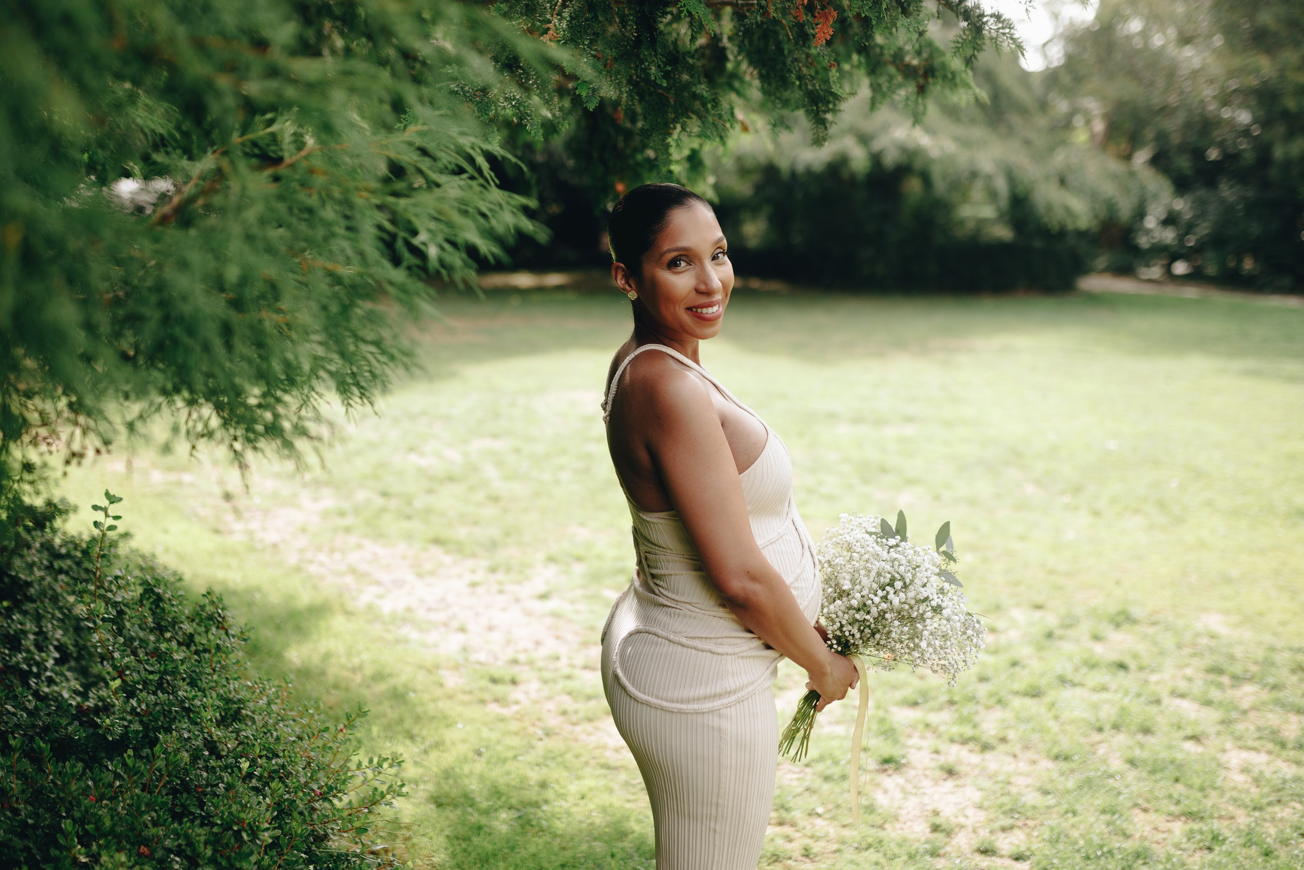 Bride in garden holding bouquet, elegant wedding look