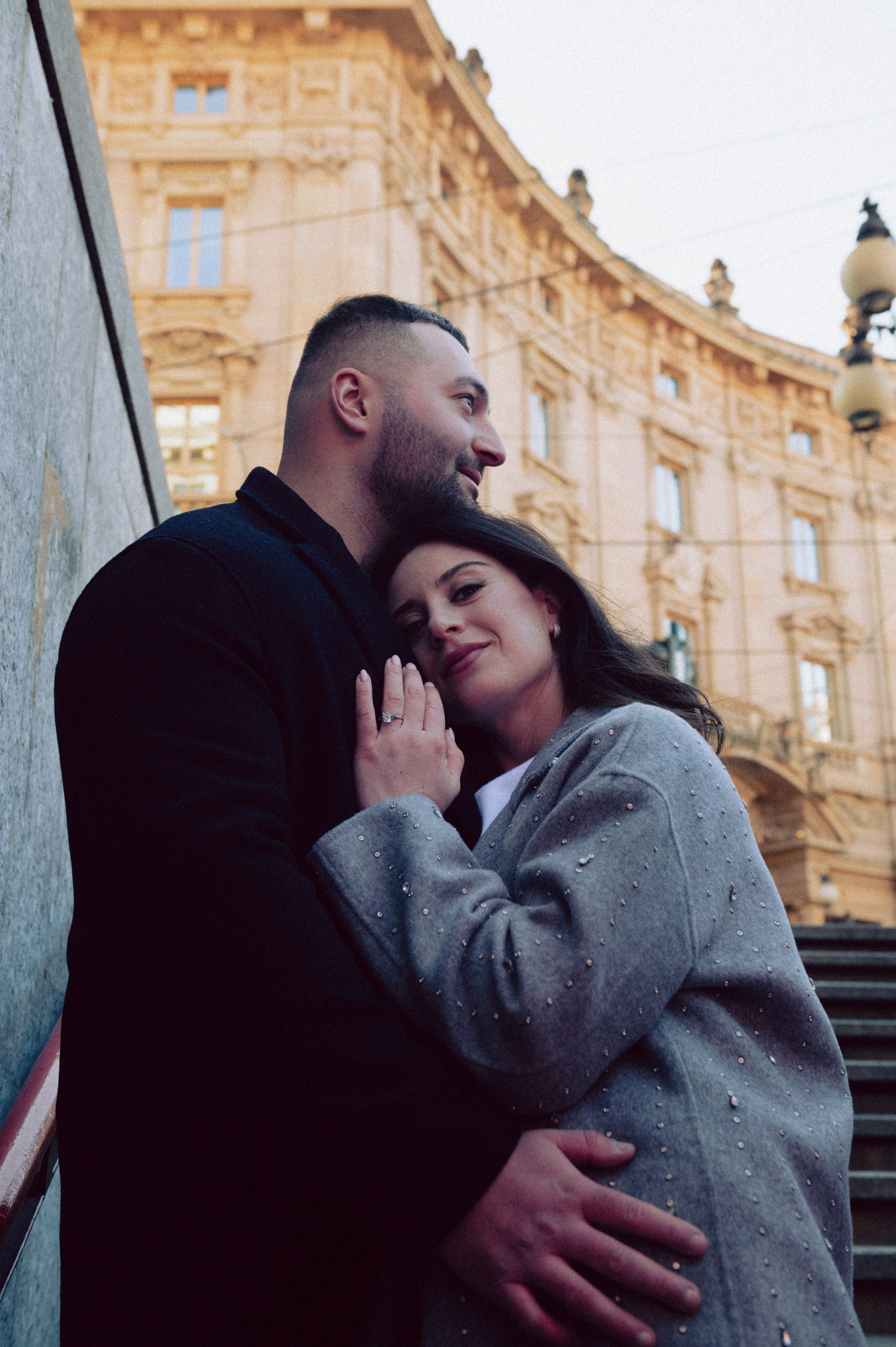 Coppia abbracciata vicino a un edificio storico di Milano, atmosfera romantica e intima durante una sessione fotografica urbana. servizio fotografico coppia Milano, coppia innamorata Italia, fotografia naturale di coppia, coppia in movimento Milano, servizio fotografico spontaneo Milano, amore e viaggio Italia, servizio fotografico di coppia Milano, fotografia love story Milano, coppia romantica Italia, ritratto di coppia Milano, primo piano coppia innamorata, fotografia emozionale Milano,