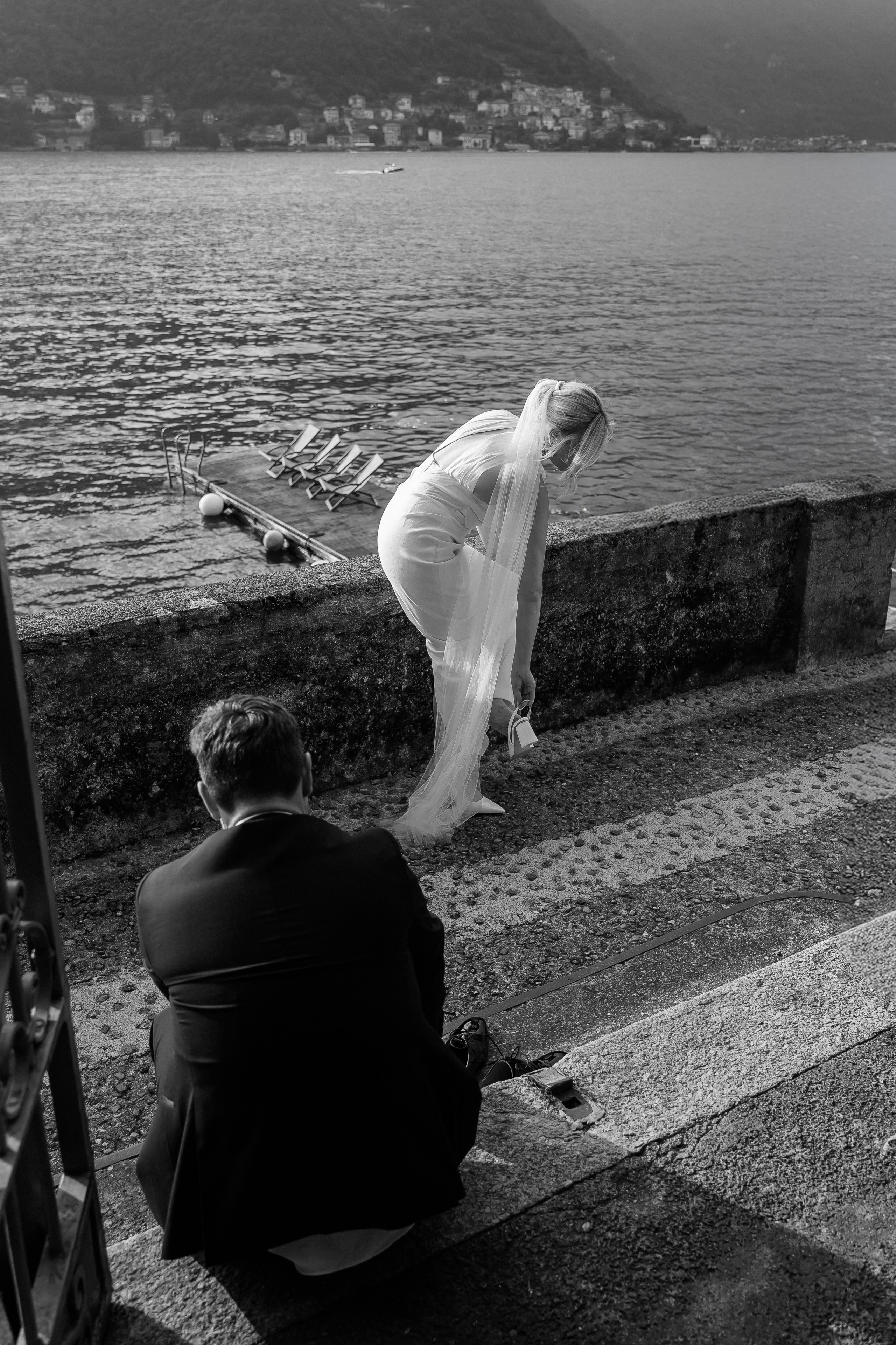 Black and white candid photo of the bride and groom by Lake Como at Villa Lario, Italy