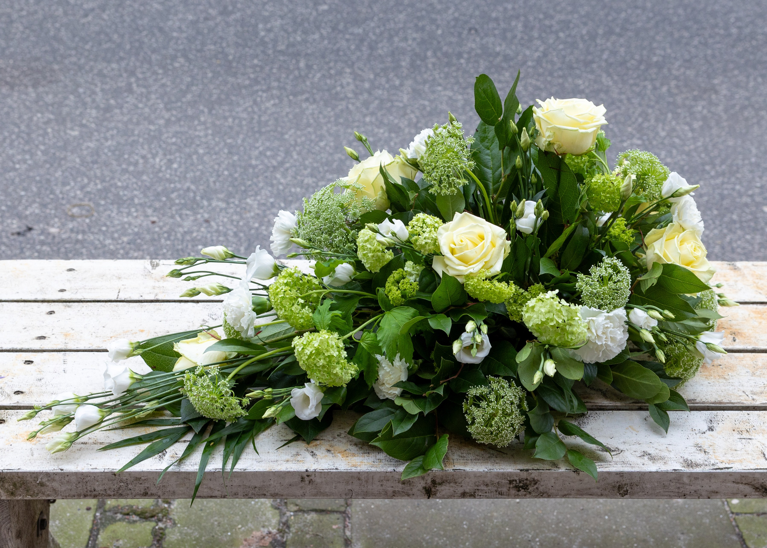 Smuk båredekoration opbygget i oasis med højde og længde på blomsterstilkene. En klassisk udført båredekoration i sæsonens lyse blomster. En elegant og smuk sidste hilsen. 