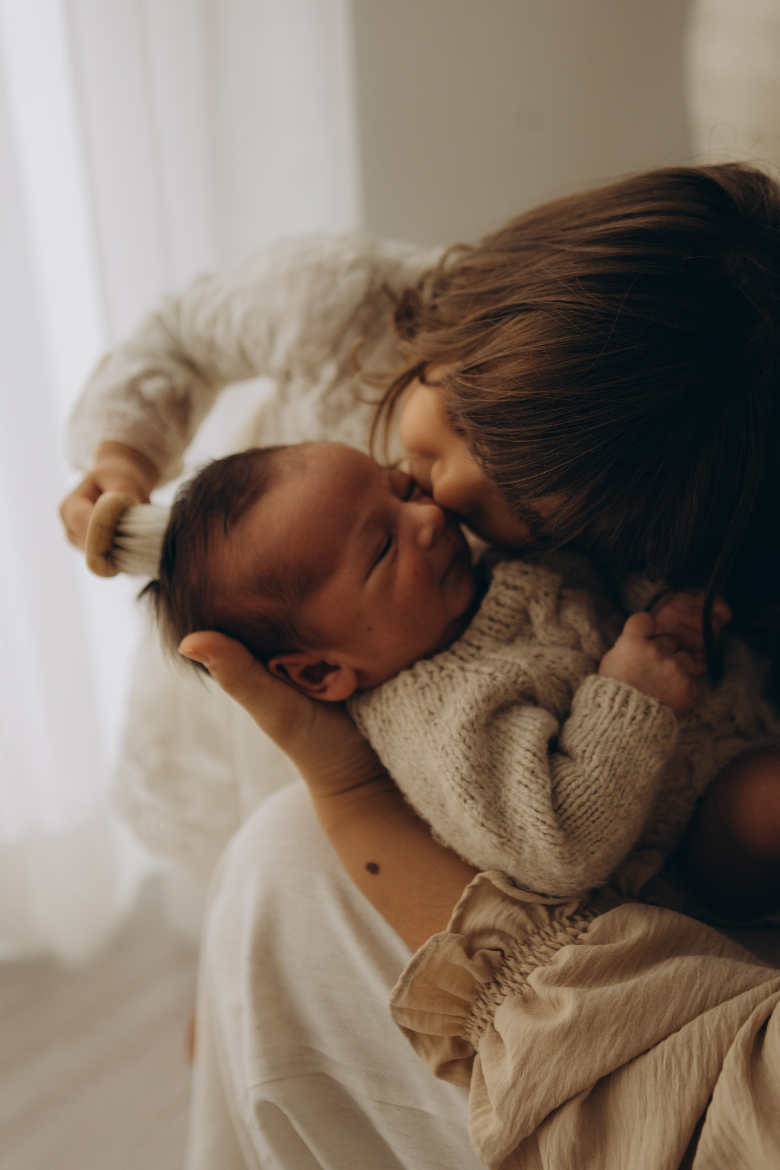 irmão beijando recém-nascido em ensaio de bebê em Sorocaba