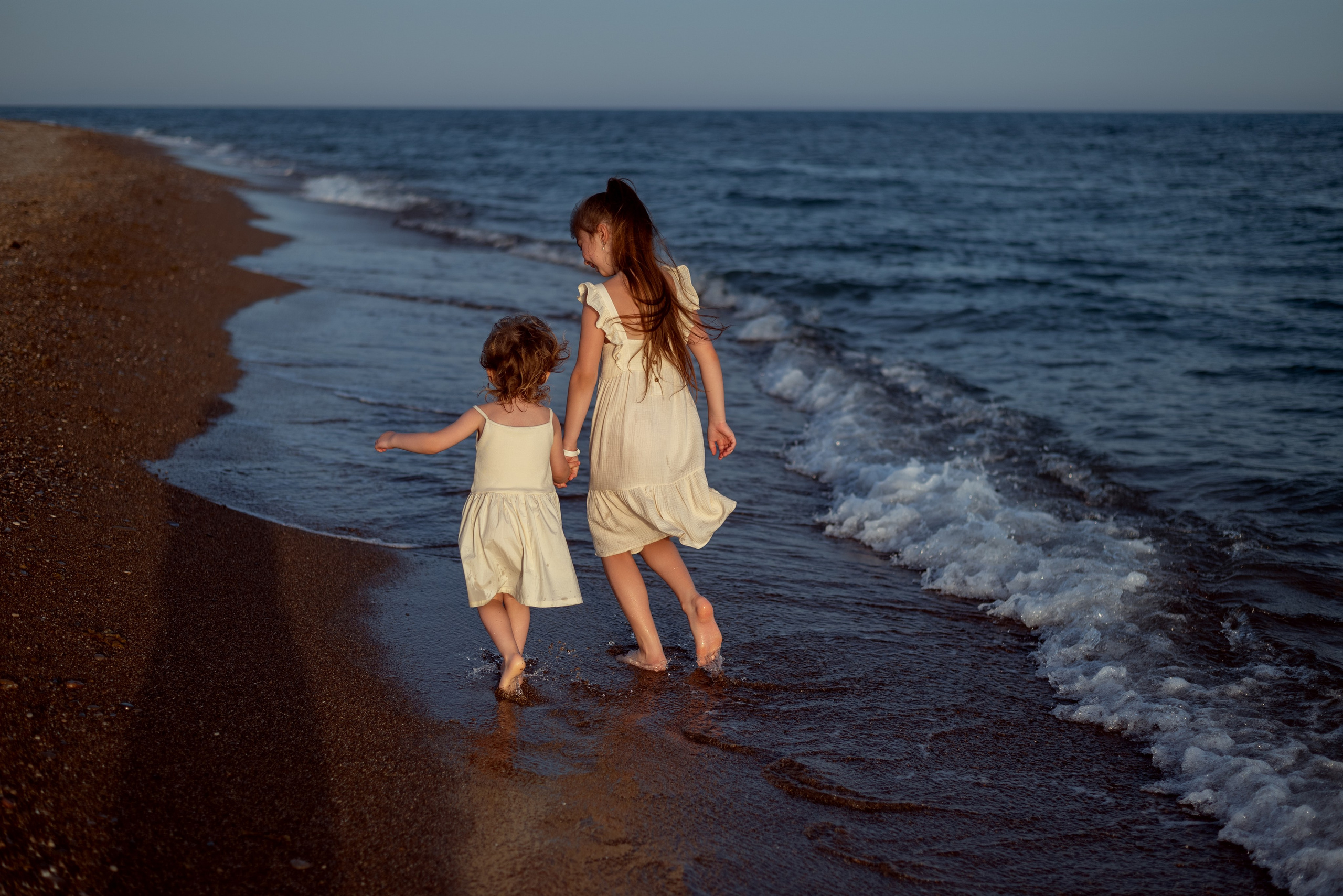 Дети бегут по берегу моря в Анталии держась за руки