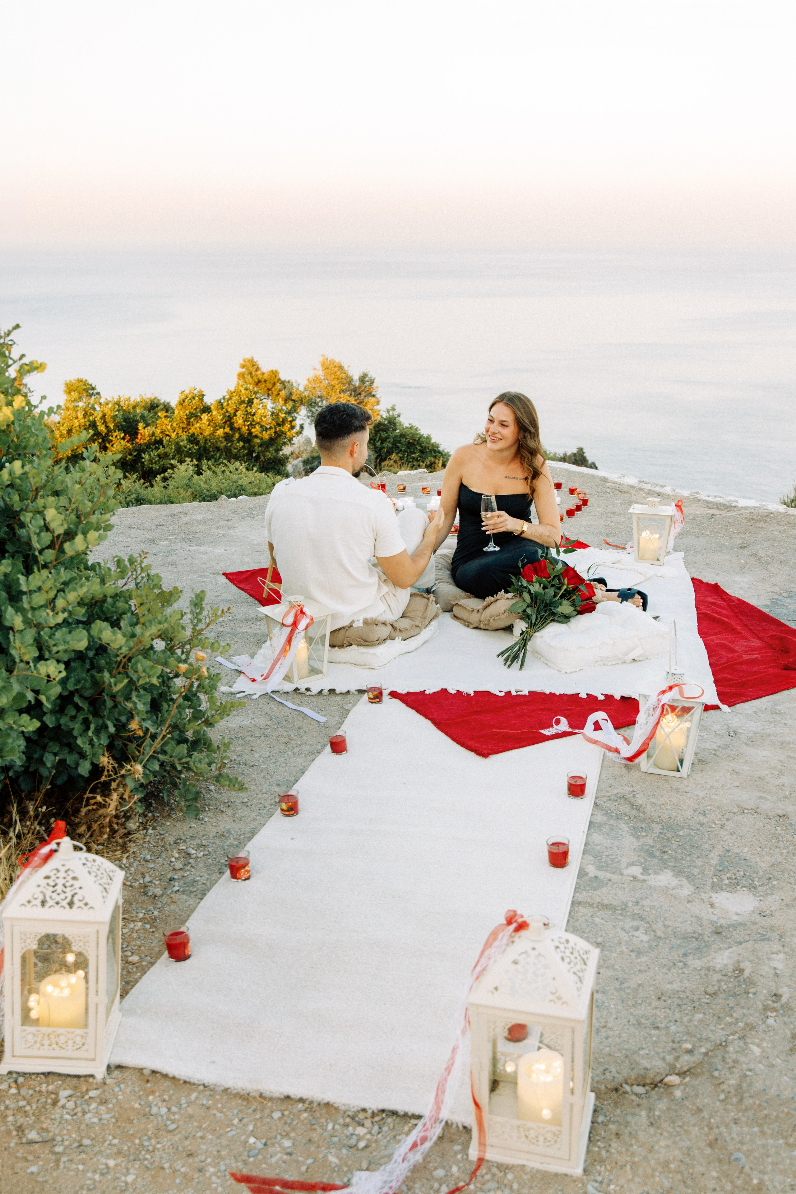 "Liebevoller Blickkontakt: Ein Paar auf dem Felsplateau des Profitis Ilias vor der Kulisse von Faliraki und dem Mittelmeer."