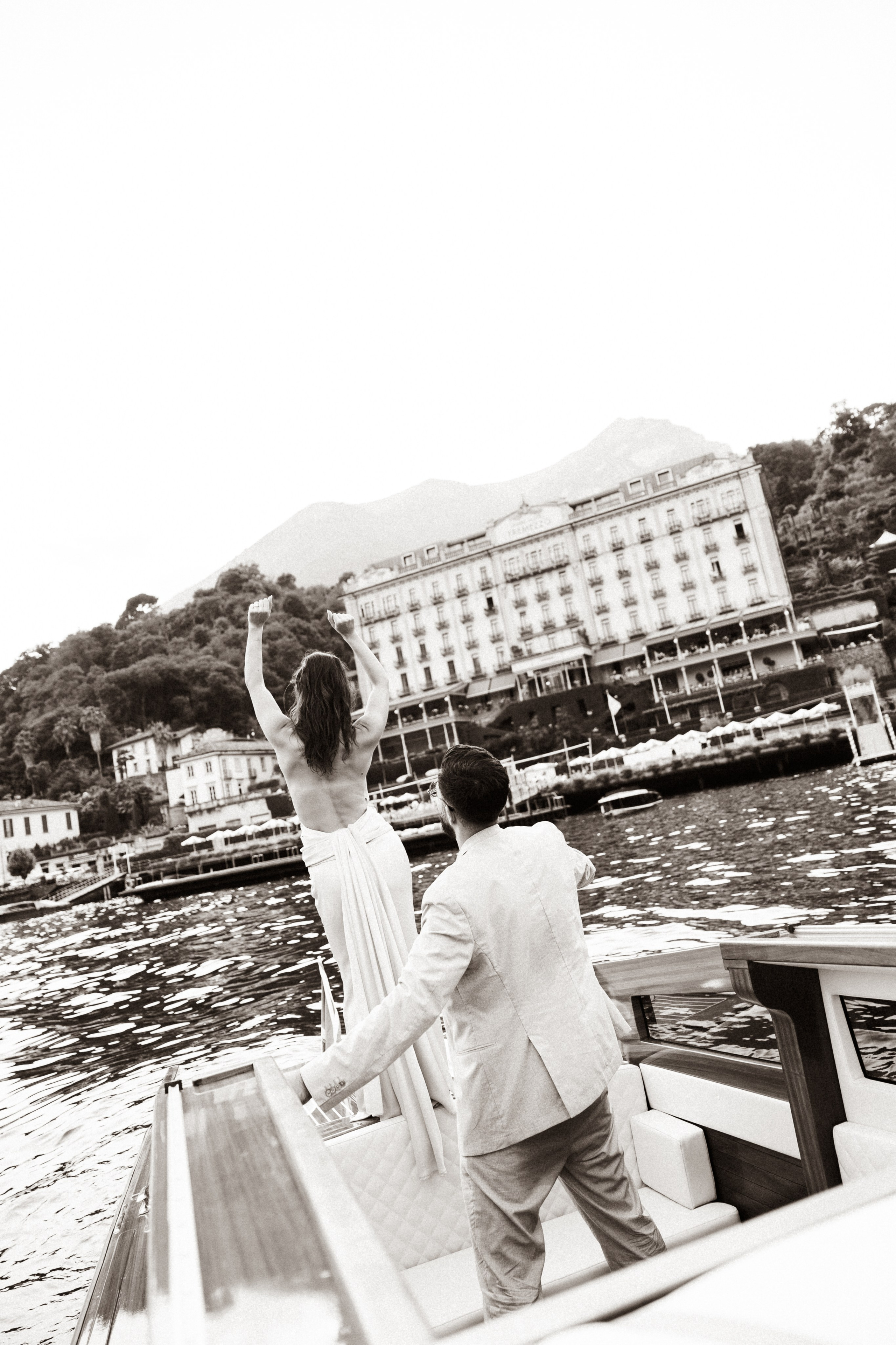 Couple on a boat overlooking Grand Hotel Tremezzo during their romantic Lake Como engagement