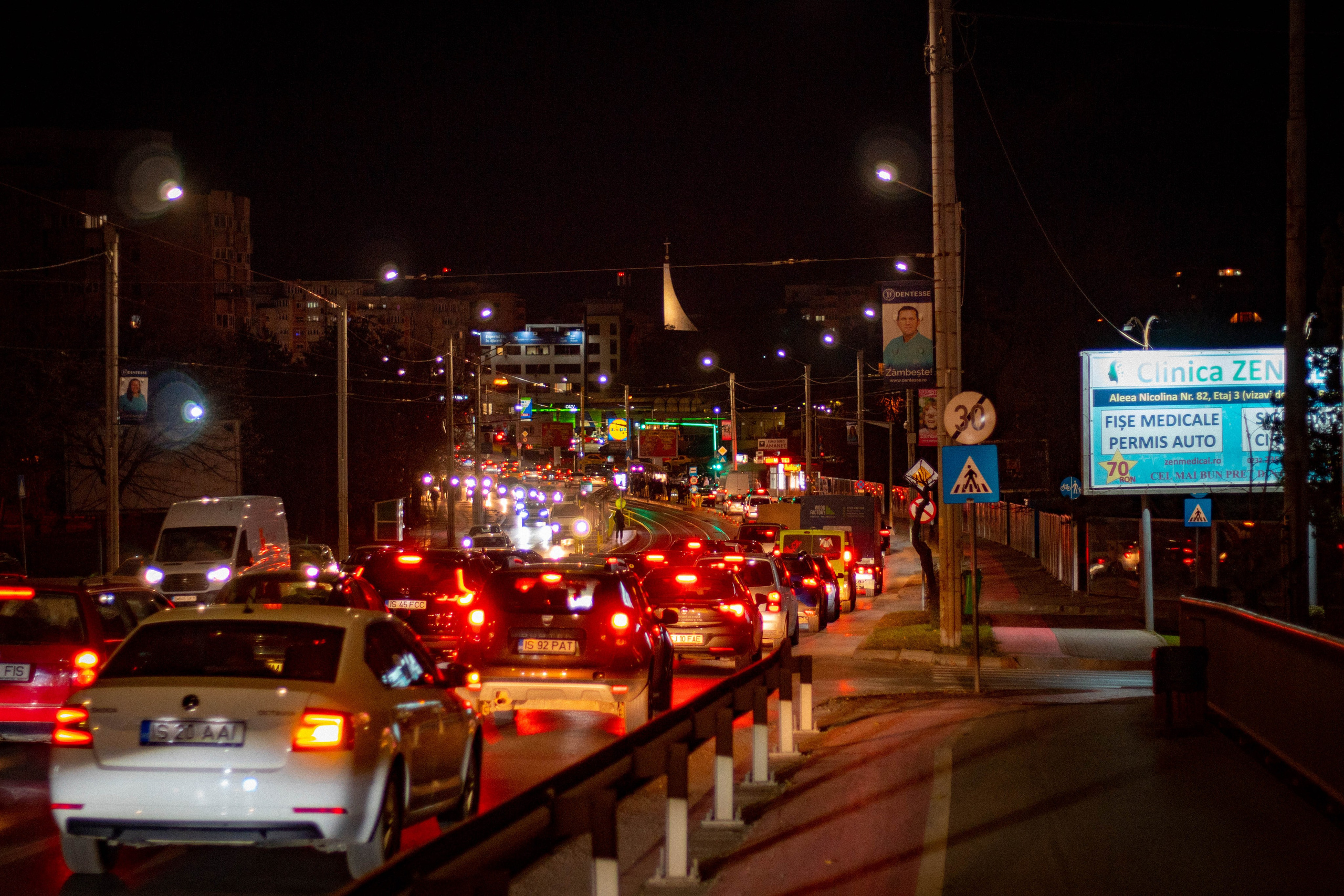 Night view of a busy city street with car headlights and traffic lights glowing.