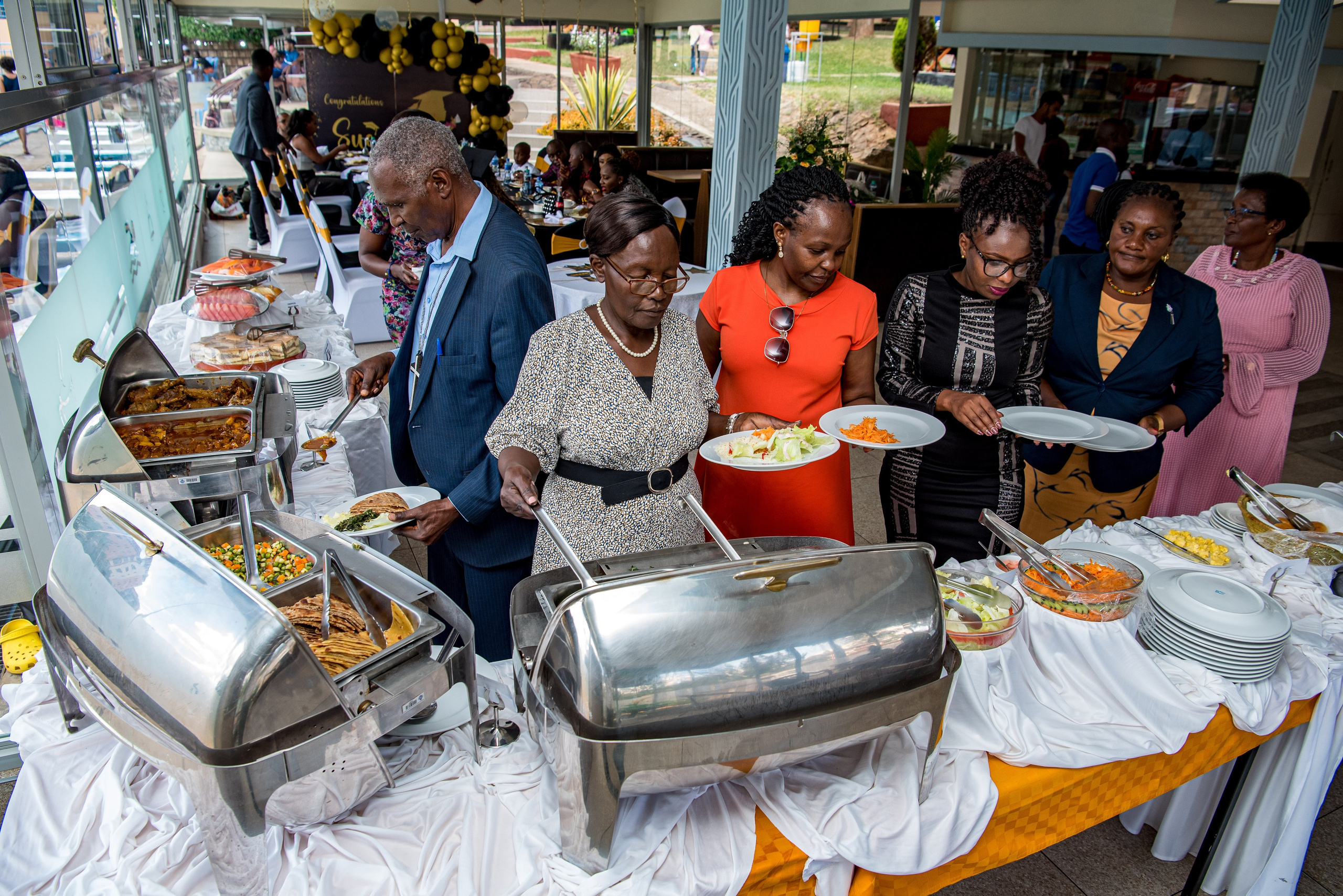 A wide shot photo of guests serving food at a graduation ceremony in Nairobi
