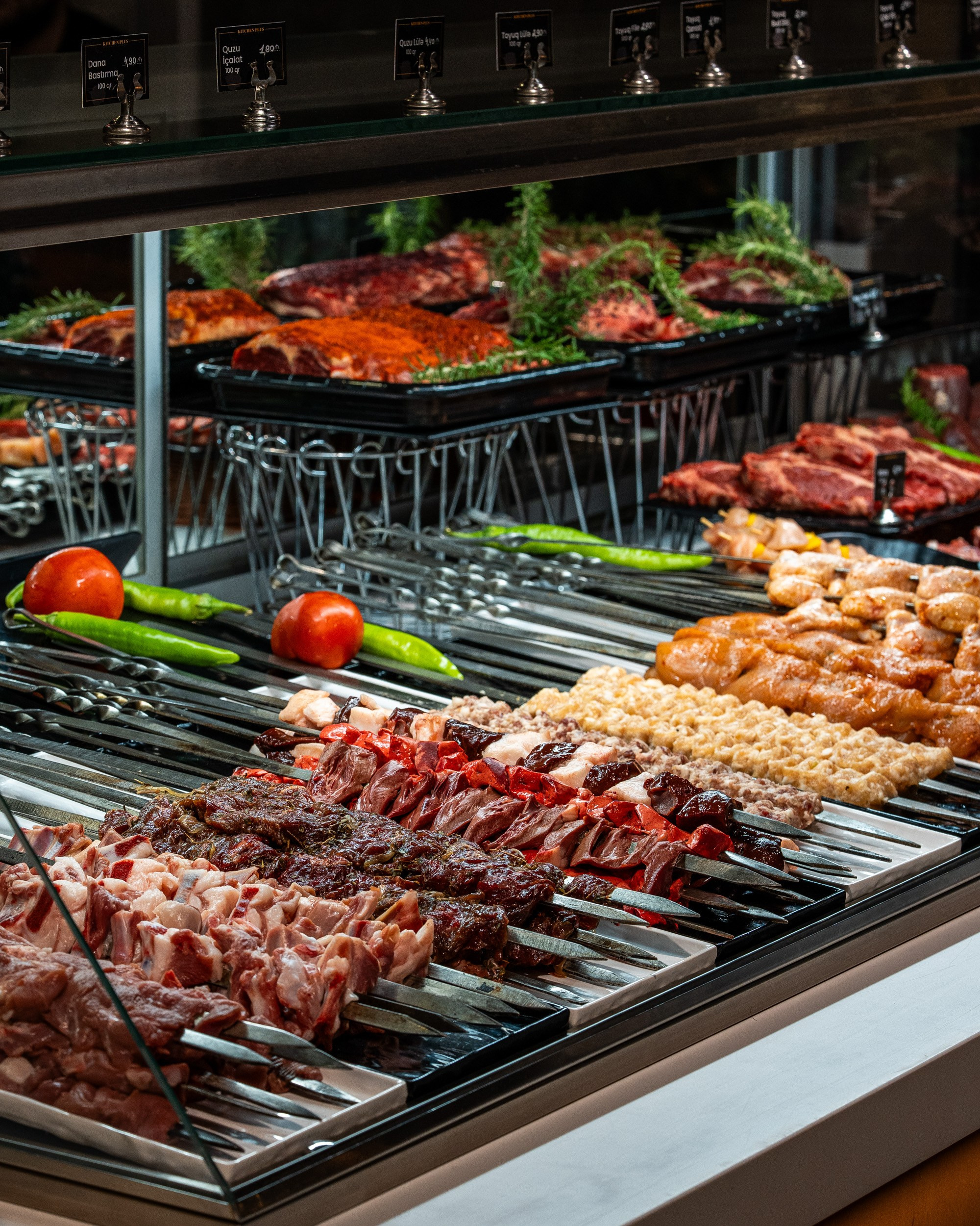 Paslanmayan polad şişlərə taxılmış müxtəlif kabab növləri (quzu, mal, toyuq) və quzu qabırğalarının nümayiş olunduğu soyuducu vitrin.