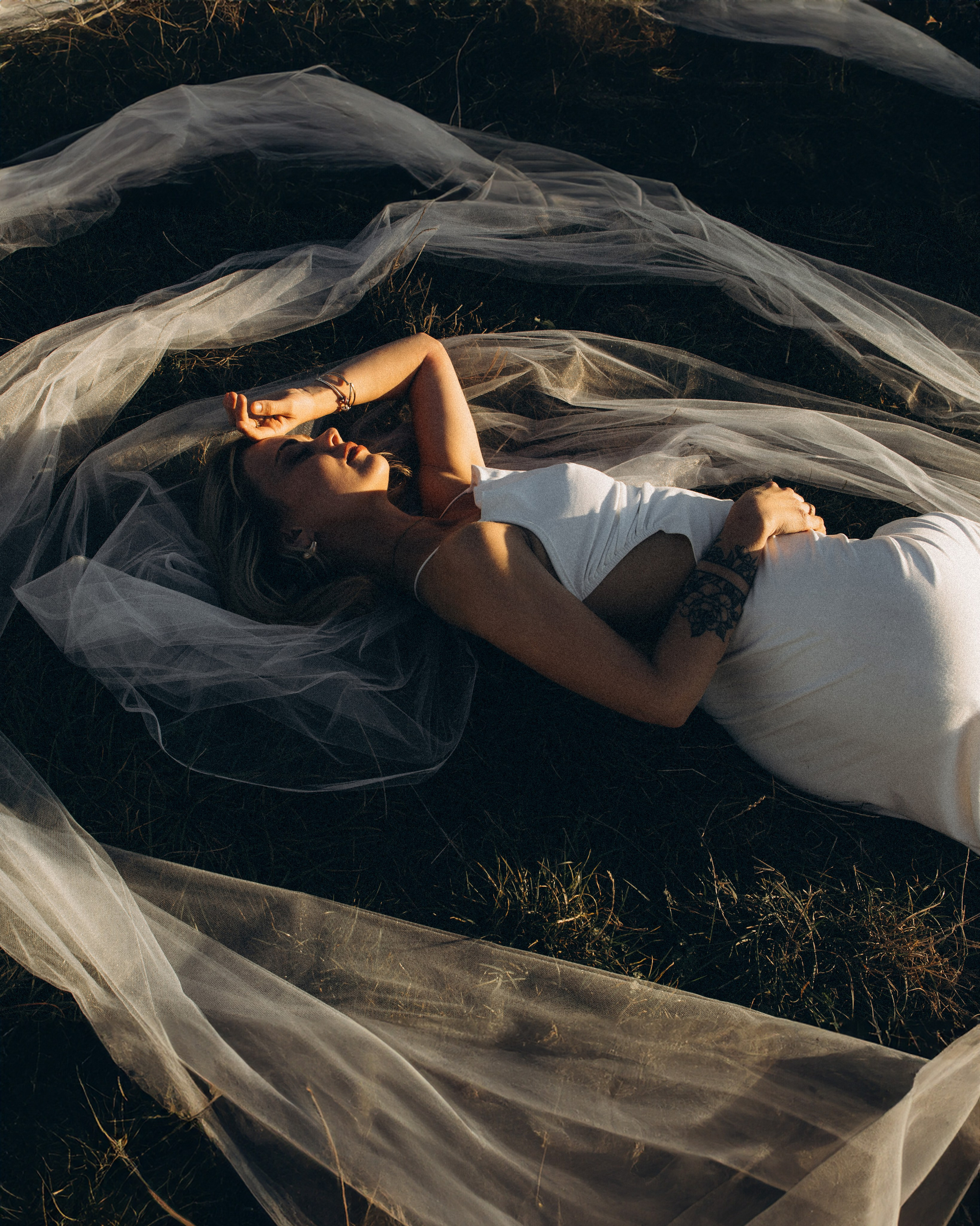 Невеста лежит на траве, укрытая фатой, мягкий свет и тишина свадебного дня в Сан-Марино