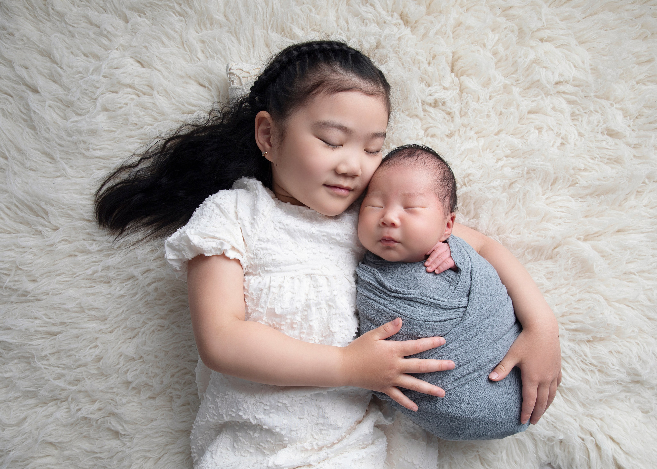 Storebror kramar sin lilla syster ömt, ett minnesvärt fotografi från fotostunden tillsammans.