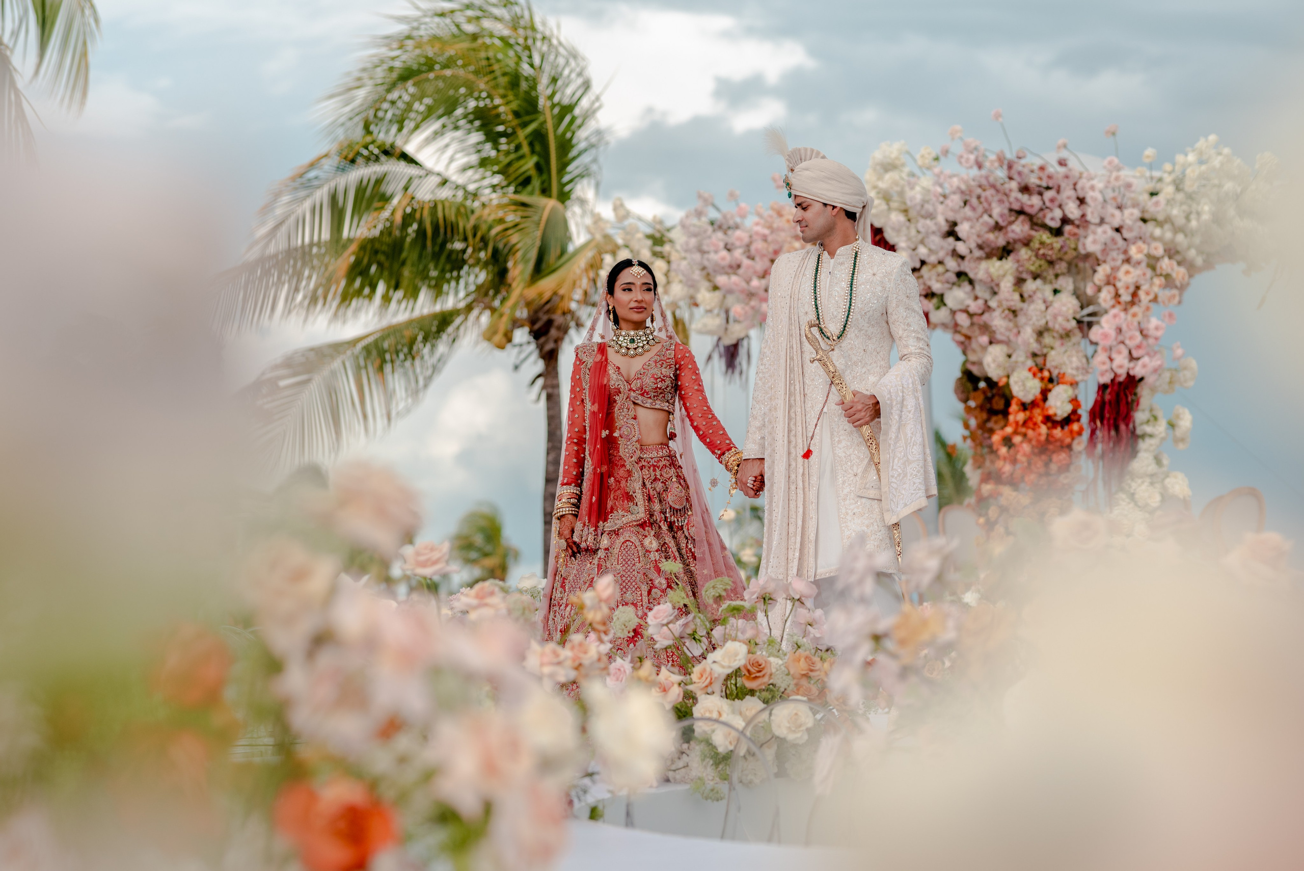 Indian bride and groom dressed in gala attire during pre Baraat photo session surrounded by flowers in Cancun Mexico