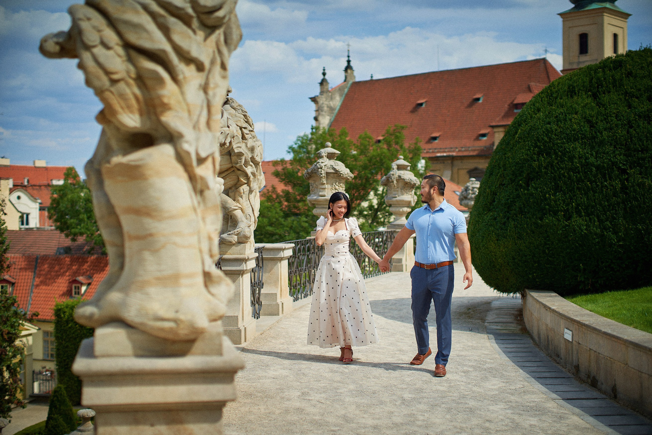 Couple walking through statue-lined landscape of Vrtba Garden, Prague.