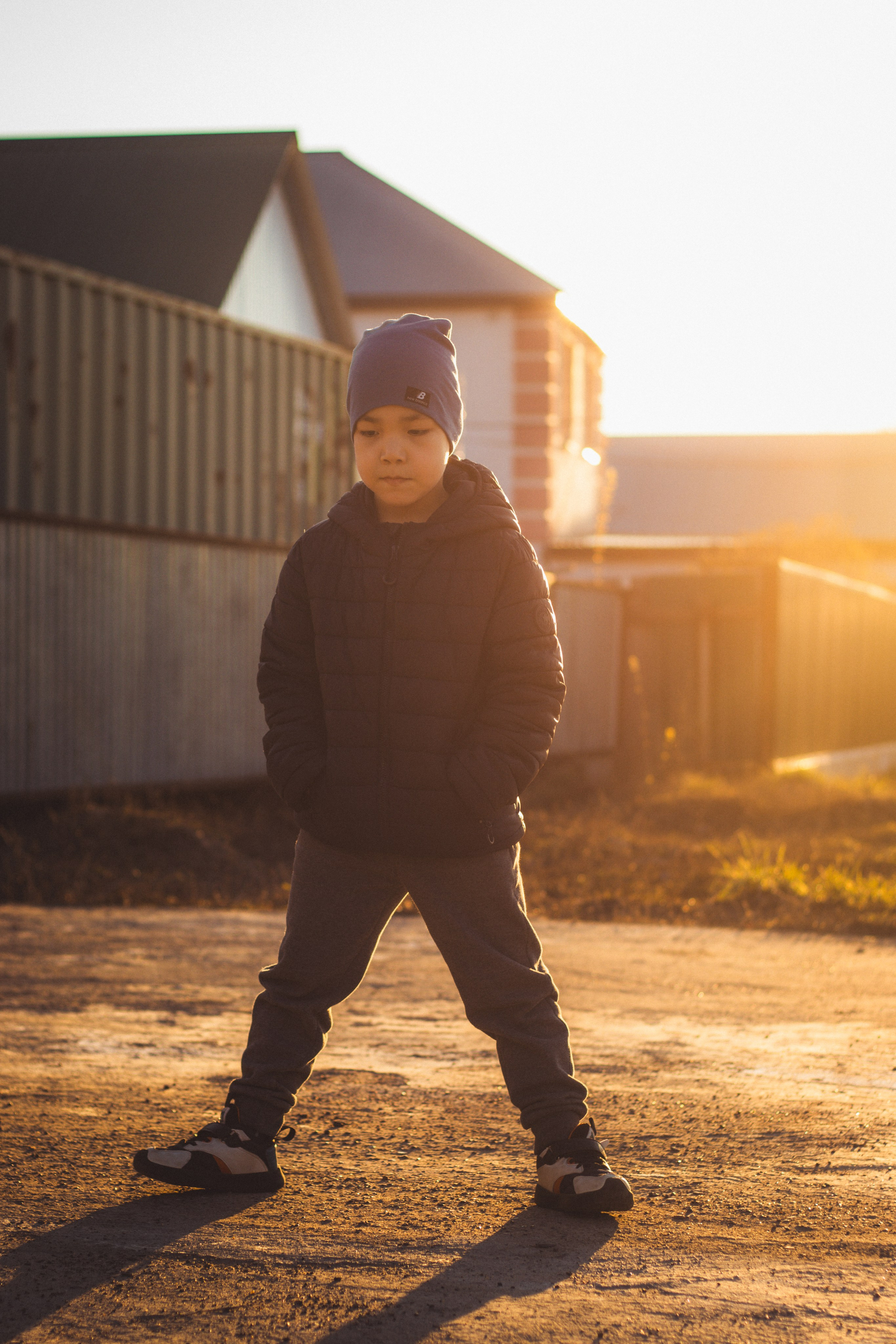 Portrét dítěte v modré čepici při západu slunce s podsvícením.