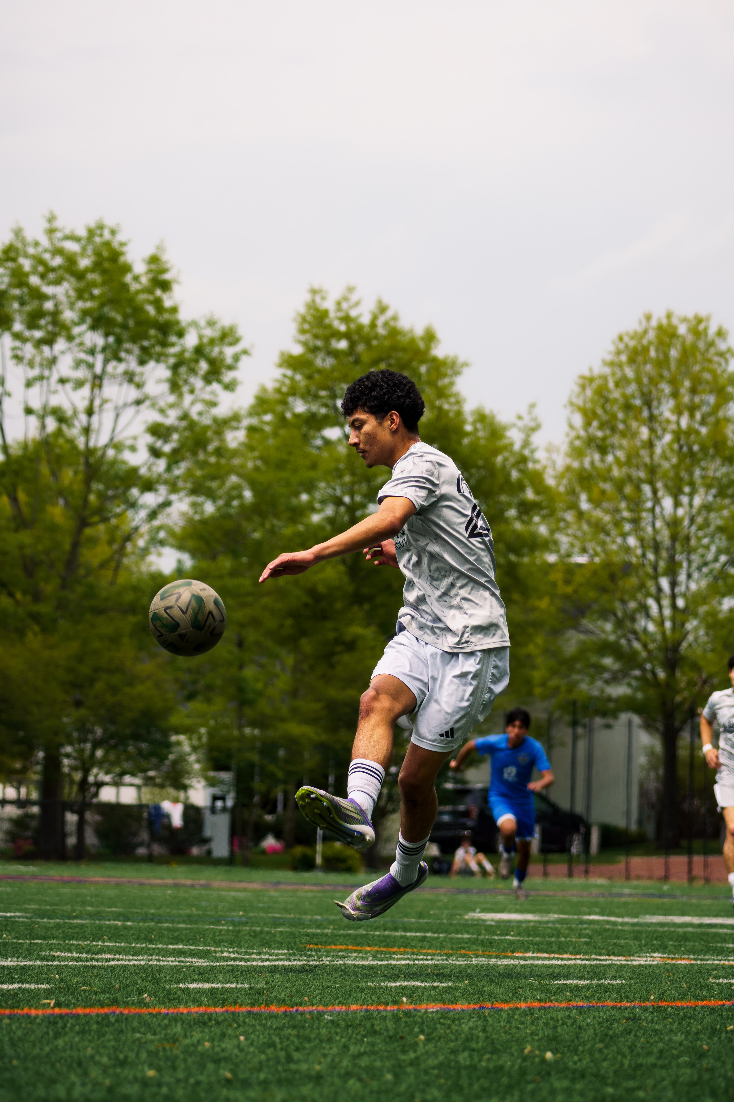 A soccer player jumps into the air to challenge and control the ball during an outdoor game.