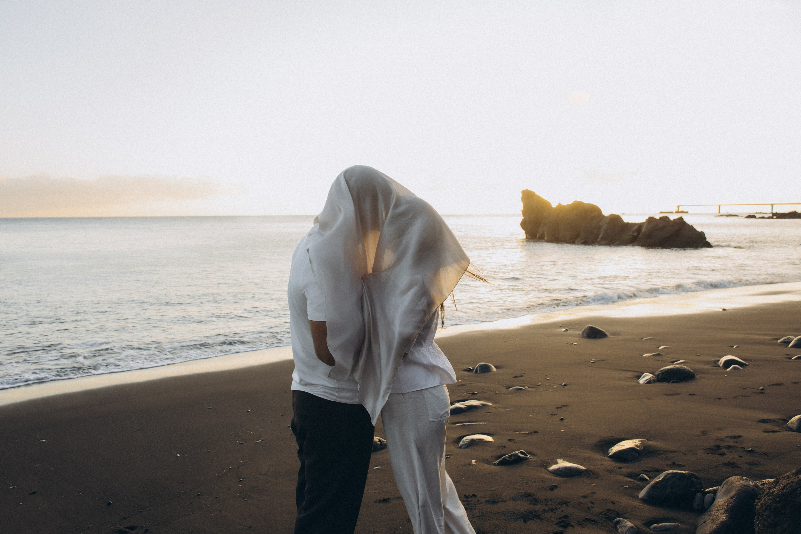 Couple sharing a romantic moment during sunset on Madeira Island, with the ocean and cliffs in the background