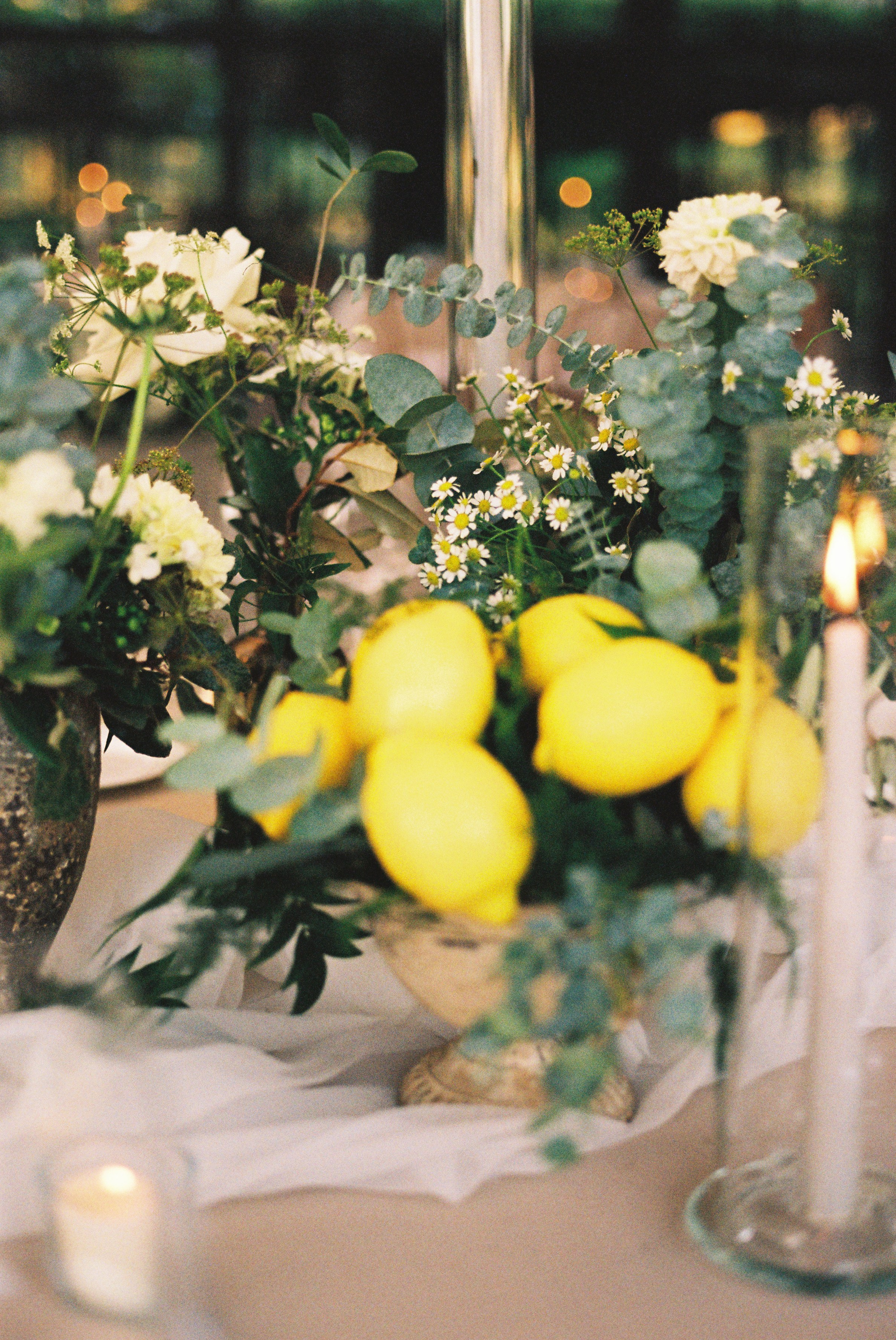 Table centerpiece featuring fresh lemons and greenery, adding vibrant color to wedding decor.