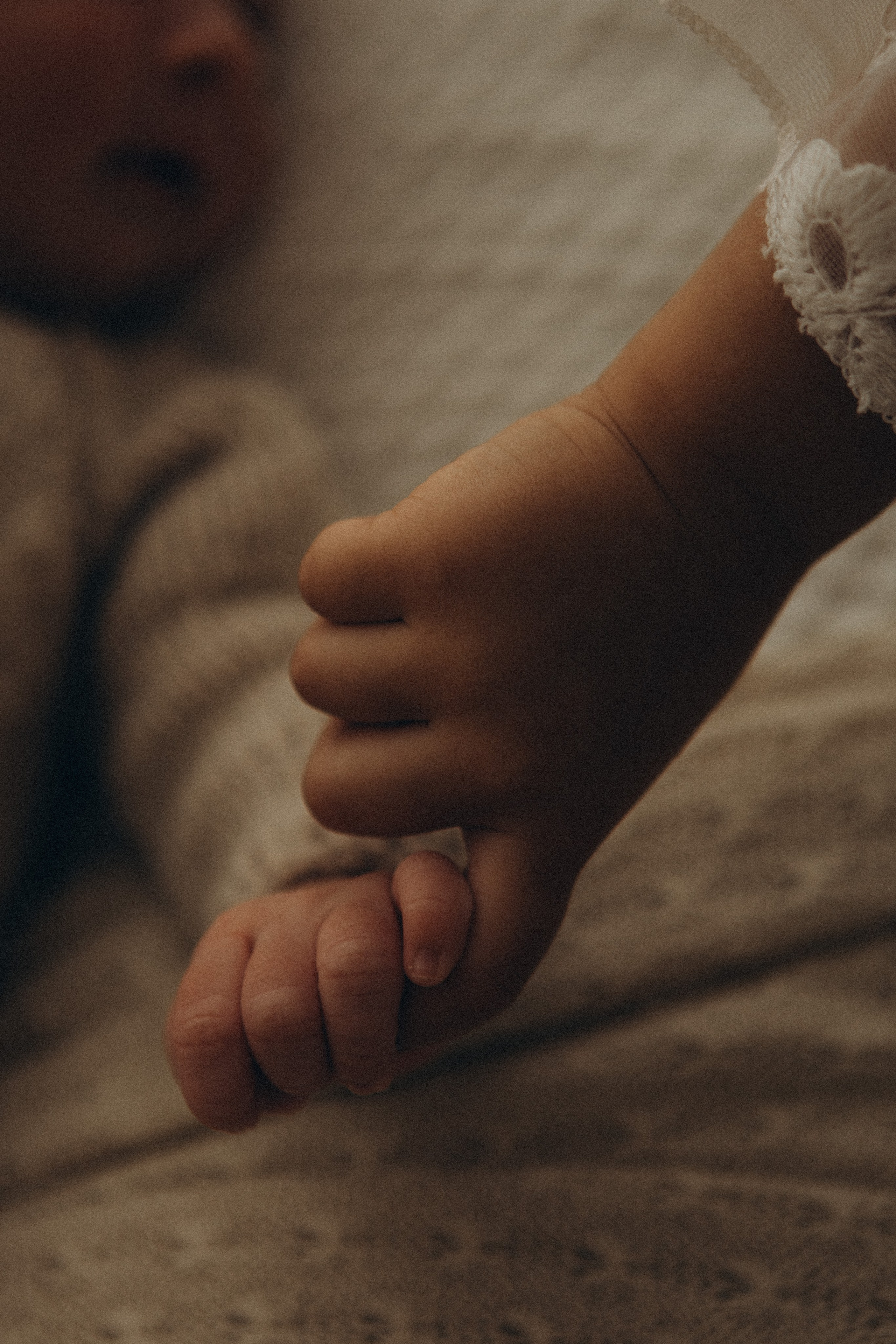 irmã mais velha segurando as mãos do recém-nascido em ensaio newborn em Sorocaba