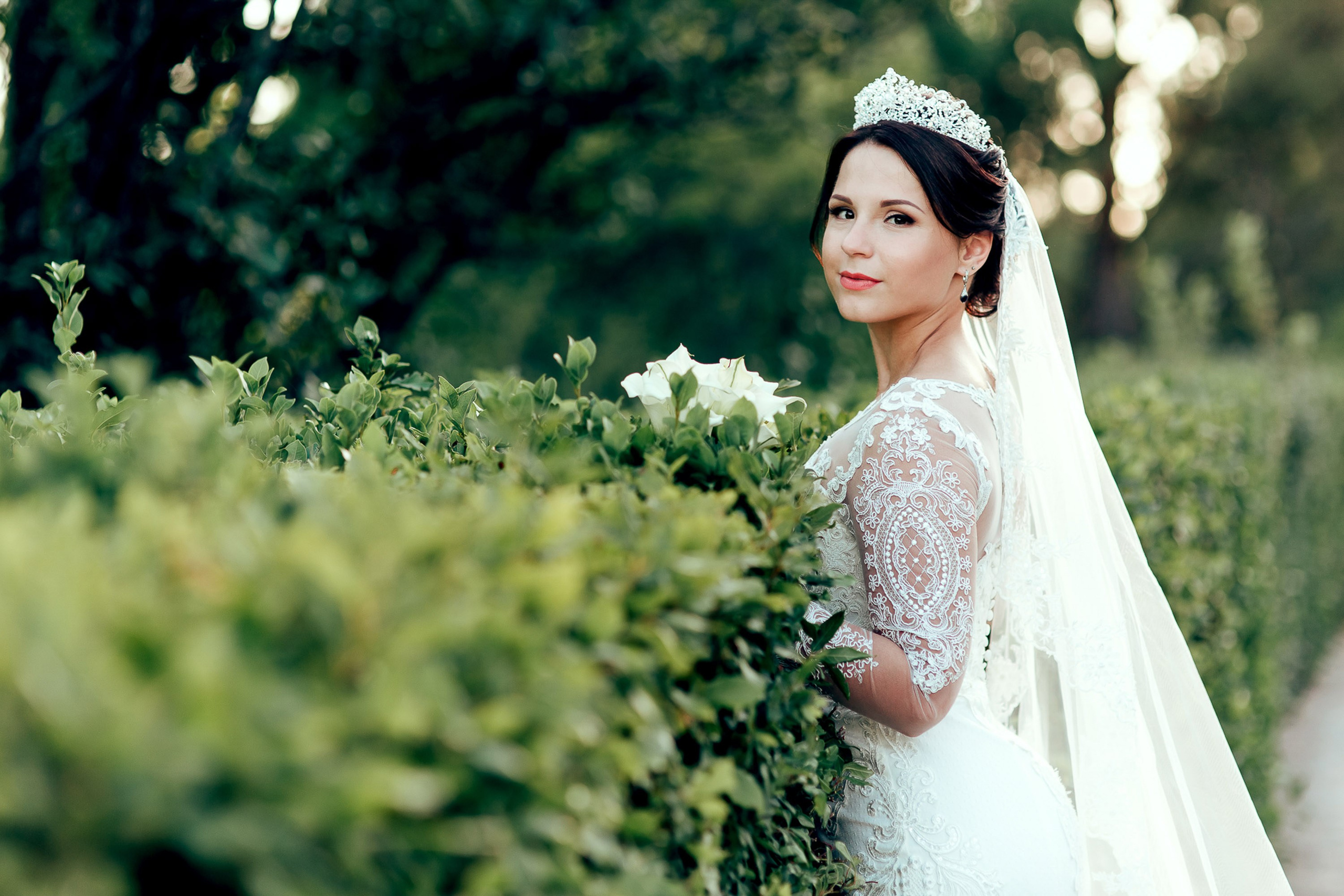 Bride smiling outdoors with bouquet, garden wedding scene