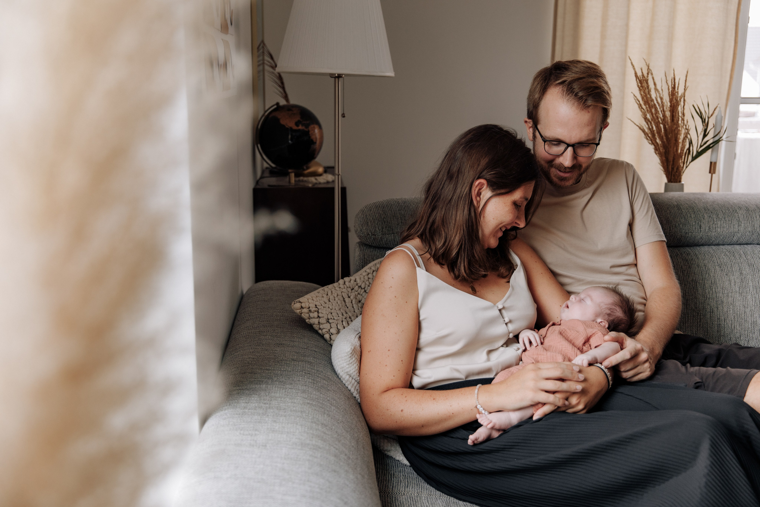 Vater steht mit seinem Sohn auf dem Arm und schaut aus dem Fenster in die Ferne.