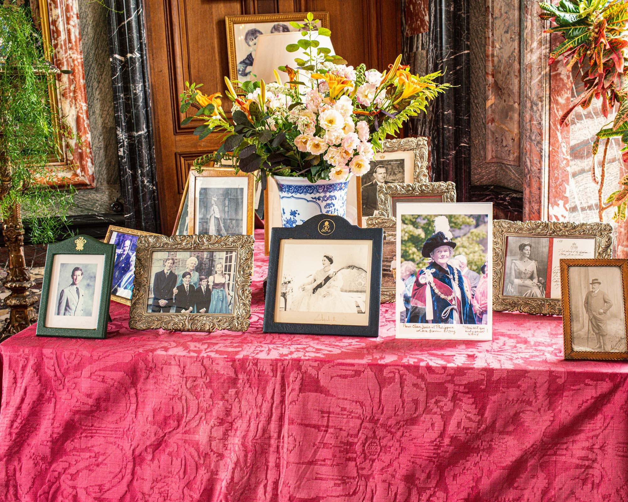 Collection of historic family photographs and floral arrangement inside Château de Courances