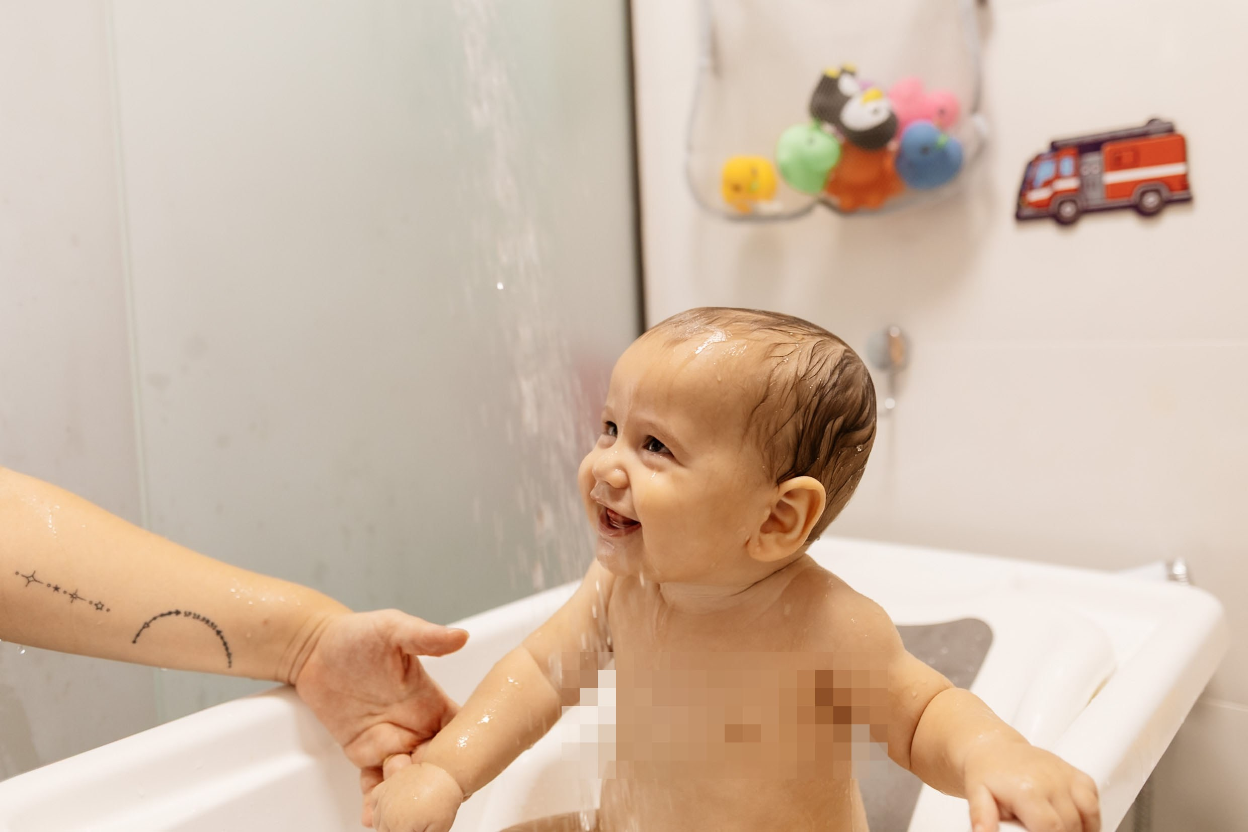 Mãos cuidam do bebê durante o banho.