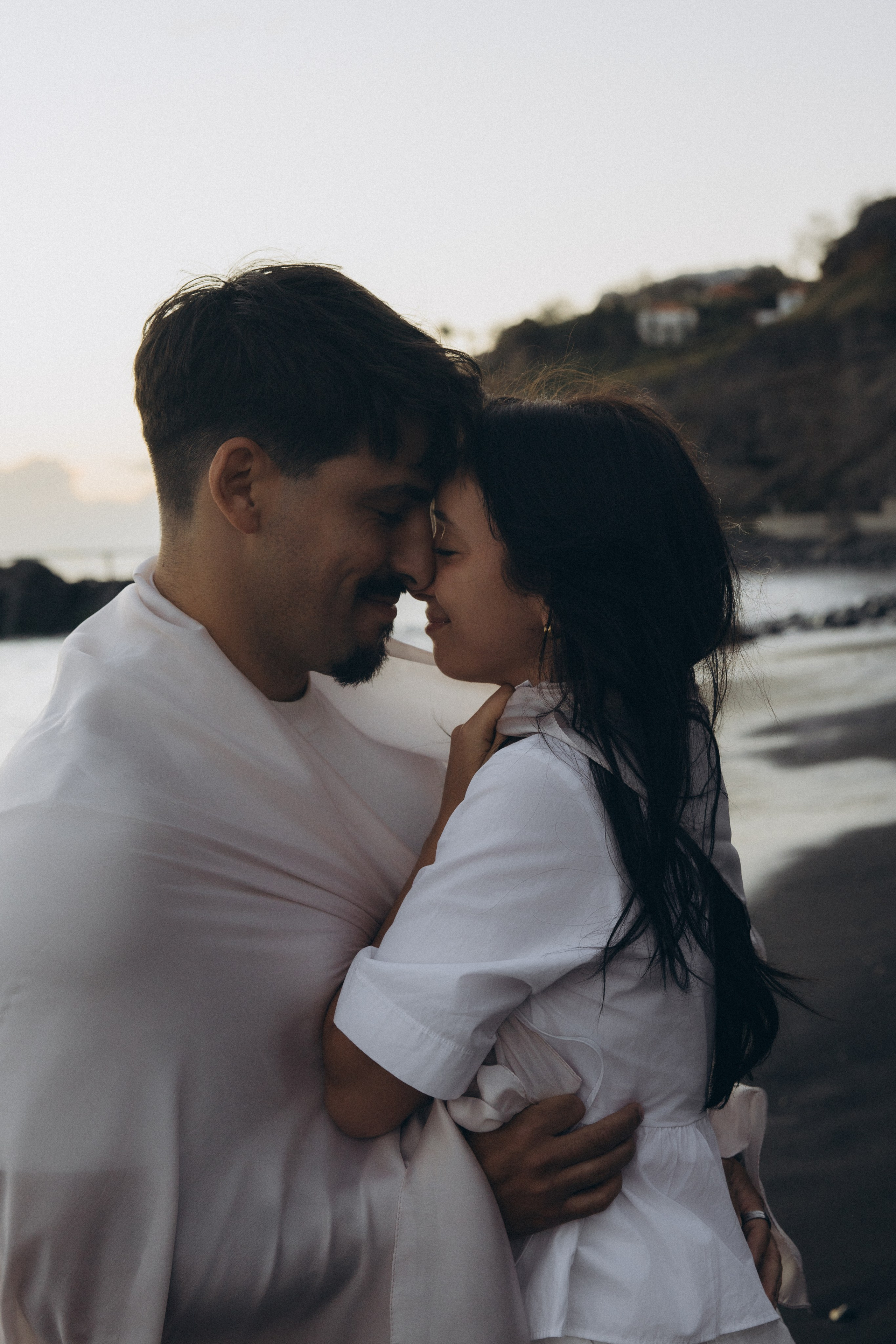 Couple sharing a romantic moment during sunset on Madeira Island, with the ocean and cliffs in the background