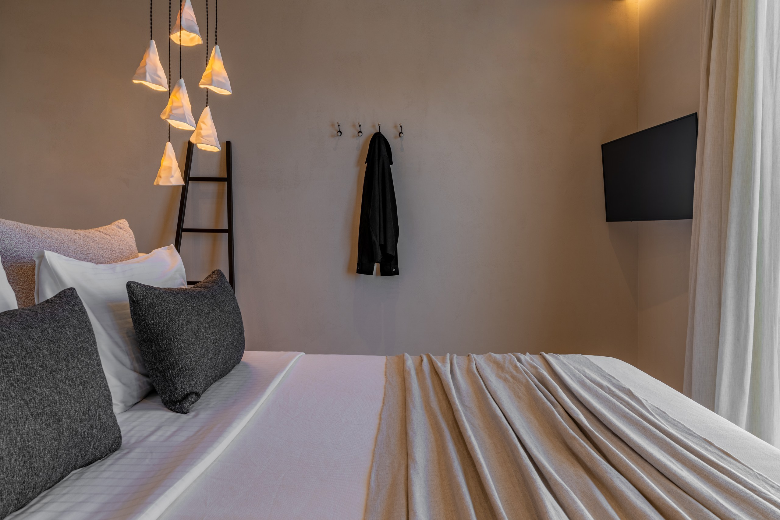 Graceful curved walls in soft rose and beige tones, illuminated by a cluster of contemporary hanging lamps. Visual narrative of the luxurious Atlantic accommodation design.