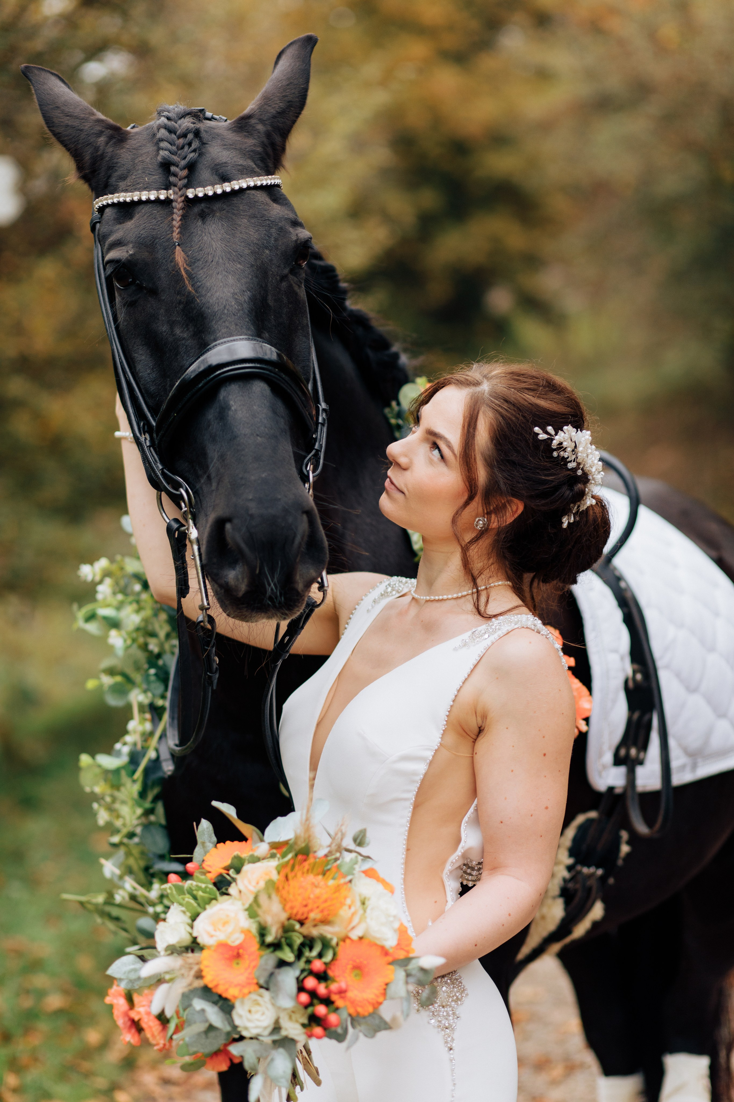 Die Braut schaut auf das Pferd und umarmt es sanft am Hals. Perfekte Hochzeitsfotos der Braut mit ihrem geliebten Pferd.
