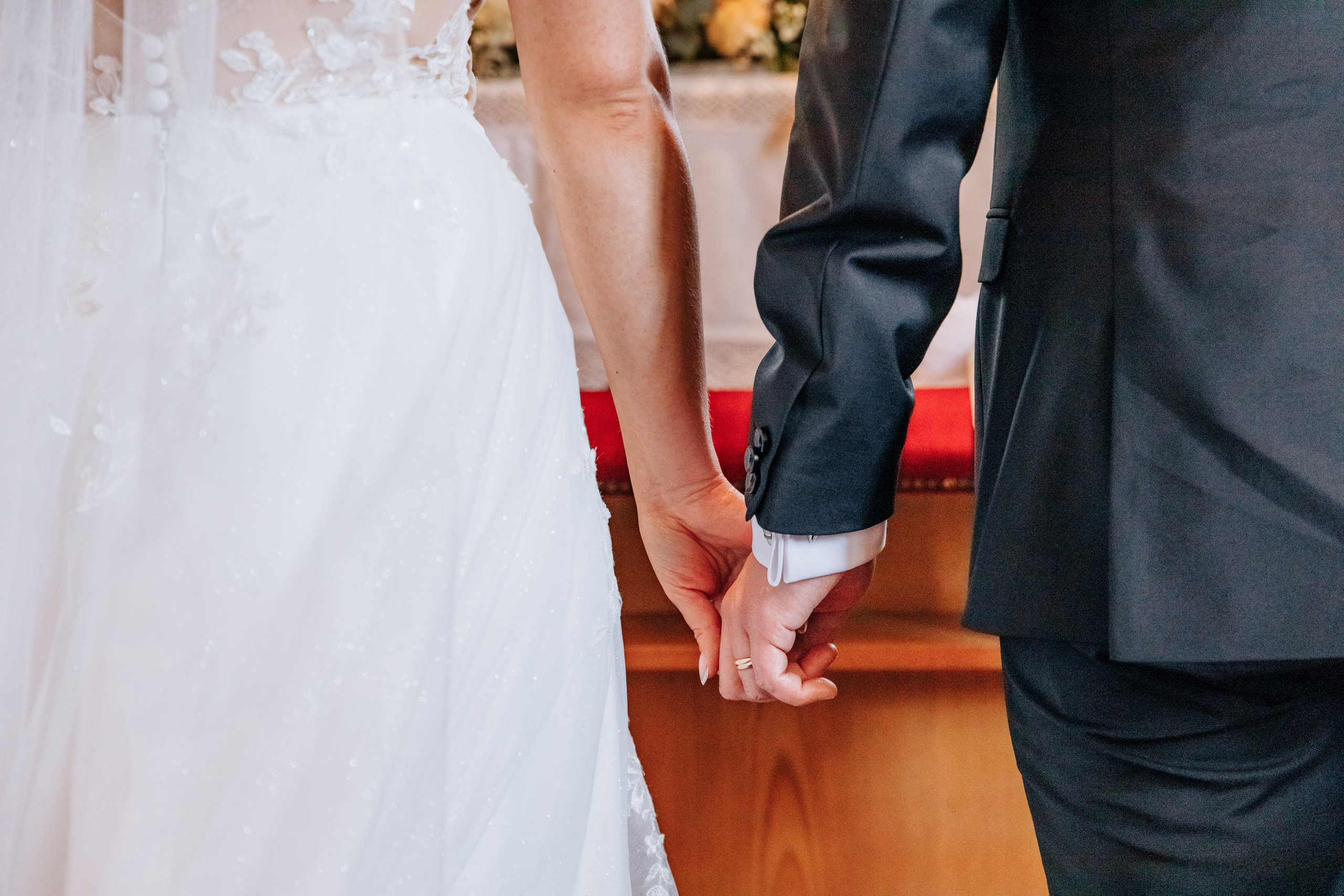 Die Hände des Brautpaares, die sich während der Hochzeitszeremonie liebevoll halten.