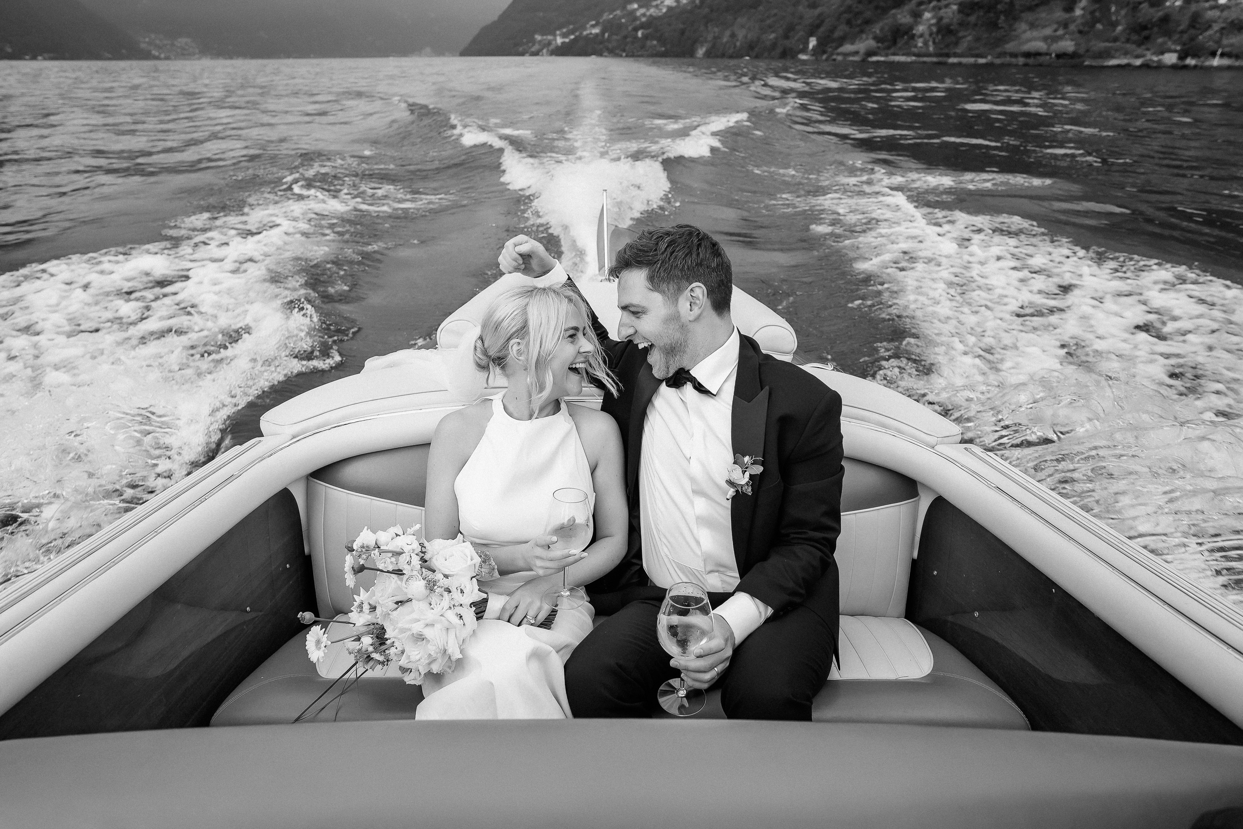 Black and white wide shot of the couple on the boat at Villa Lario, Lake Como, Italy