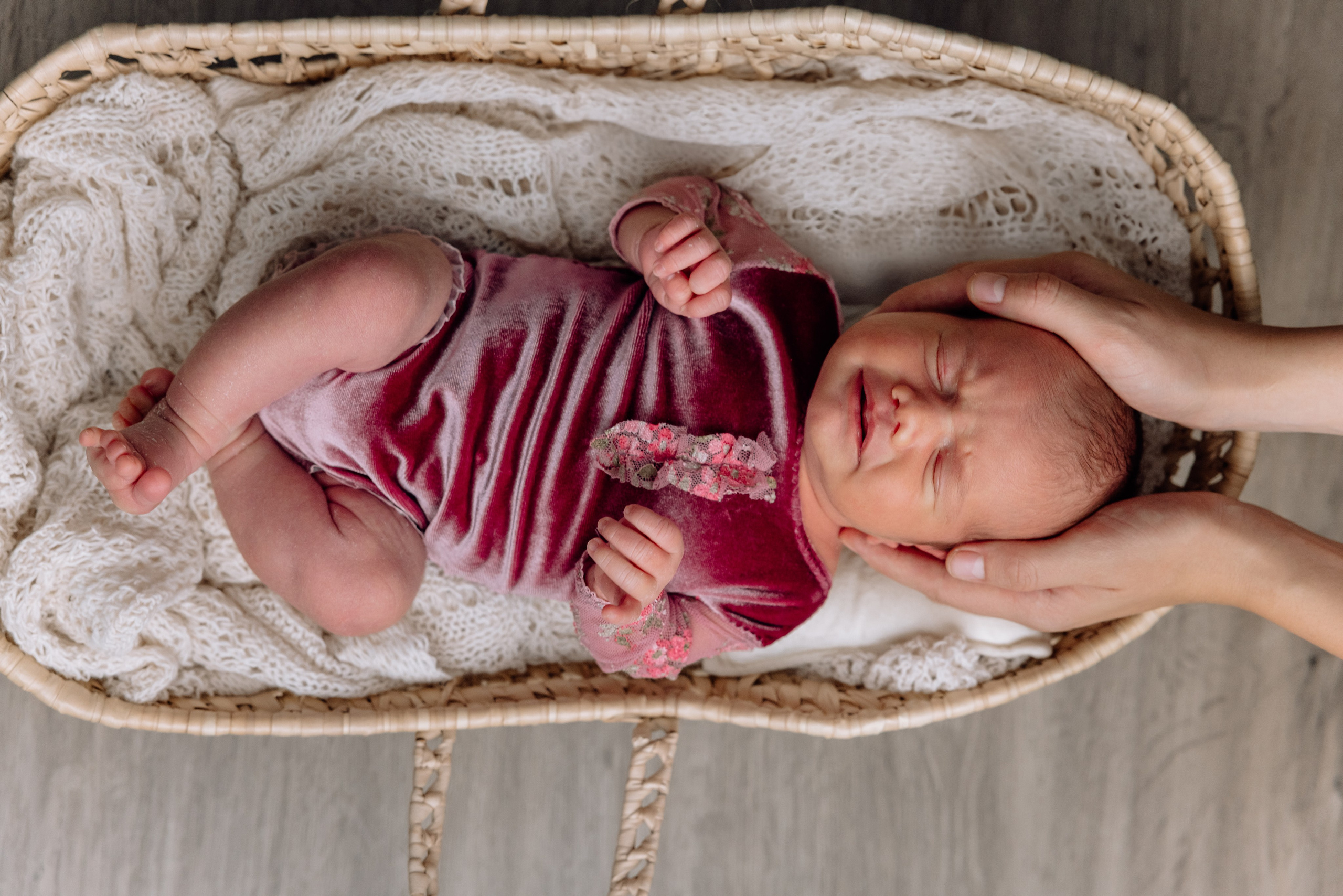 Neugeborenes im Korb, gehalten von liebevollen Händen der Mutter – Familienshooting zuhause
