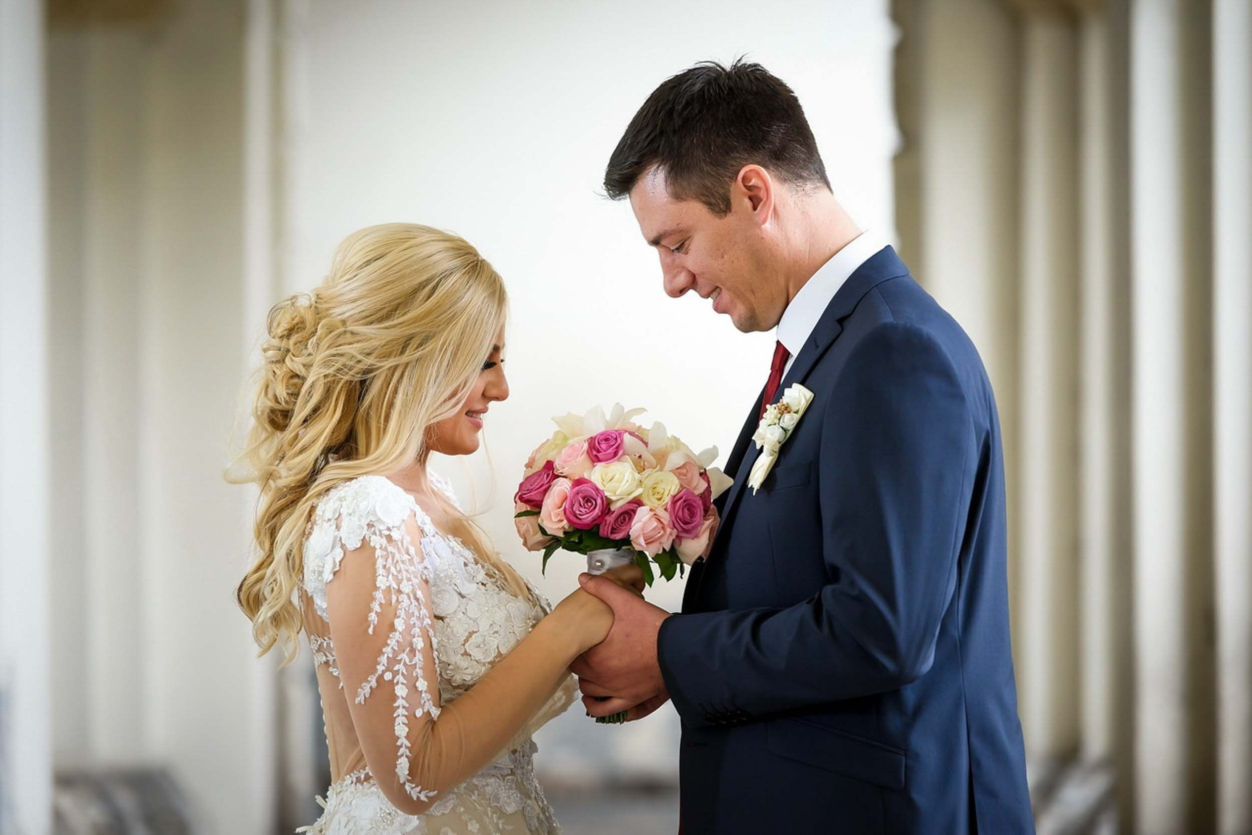 Emotivan trenutak mladenaca – mladoženja i mlada drže venčani buket, simbol ljubavi i zajedništva