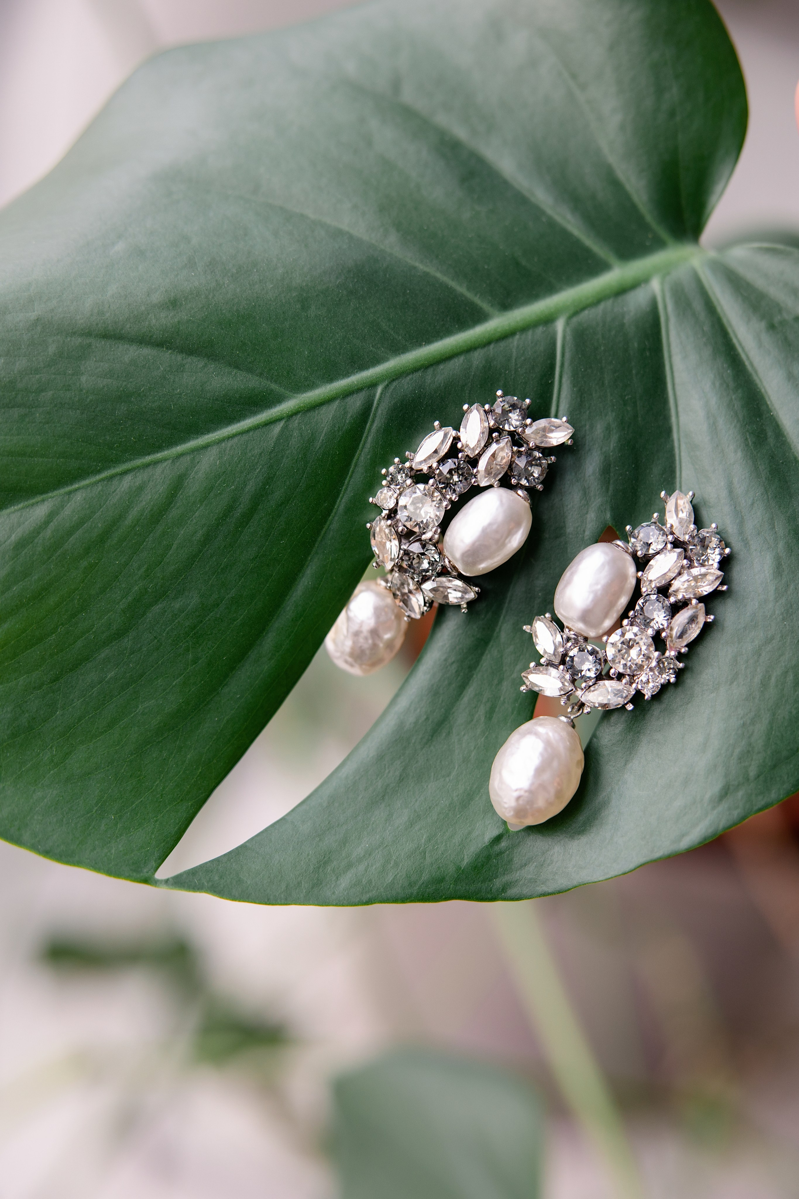 Pendientes de perlas y cristales sobre una hoja verde, detalle de novia para boda en Valencia