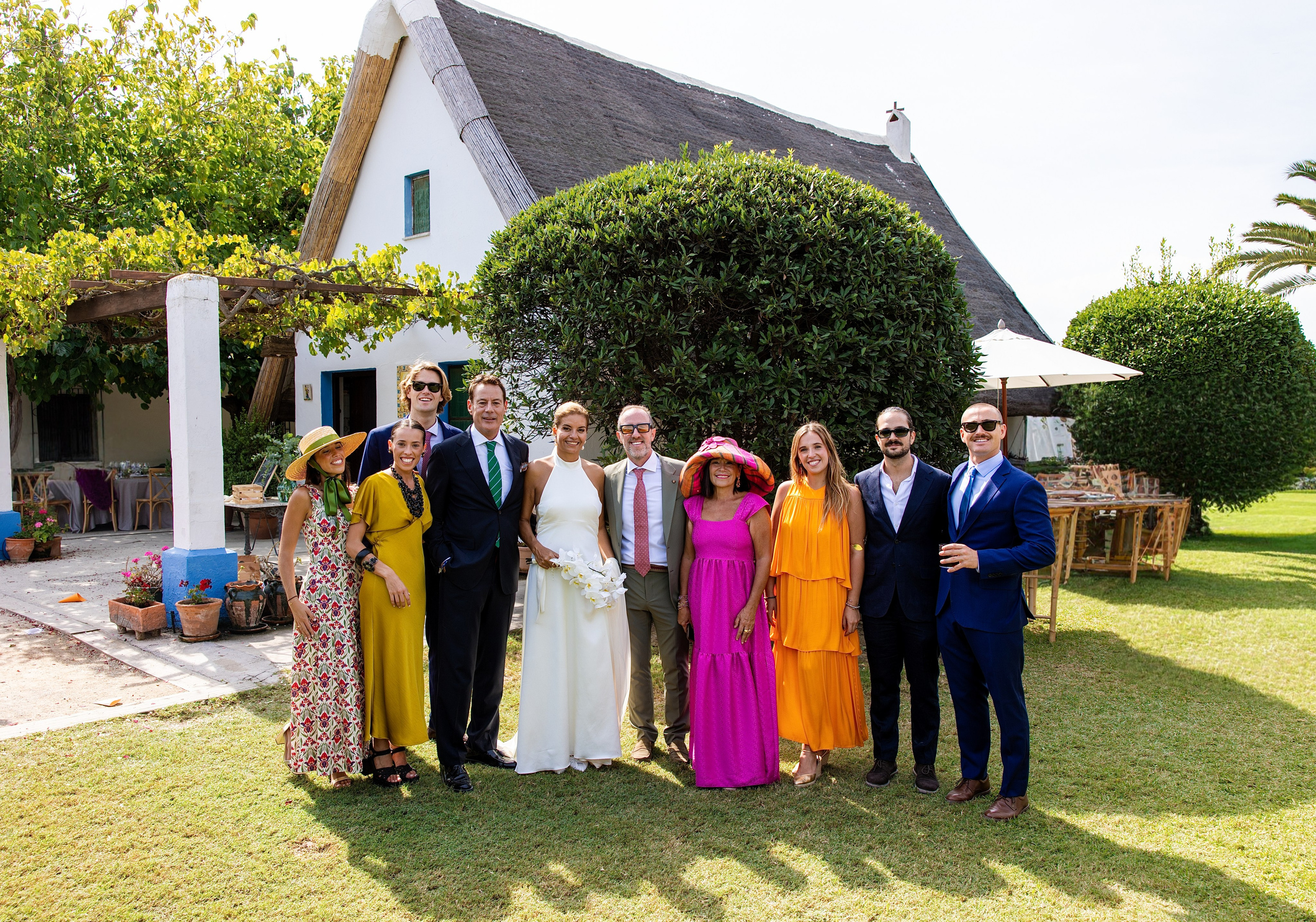 Foto de grupo de invitados con vestidos de colores delante de la barraca, boda en La Baraca del Palmar