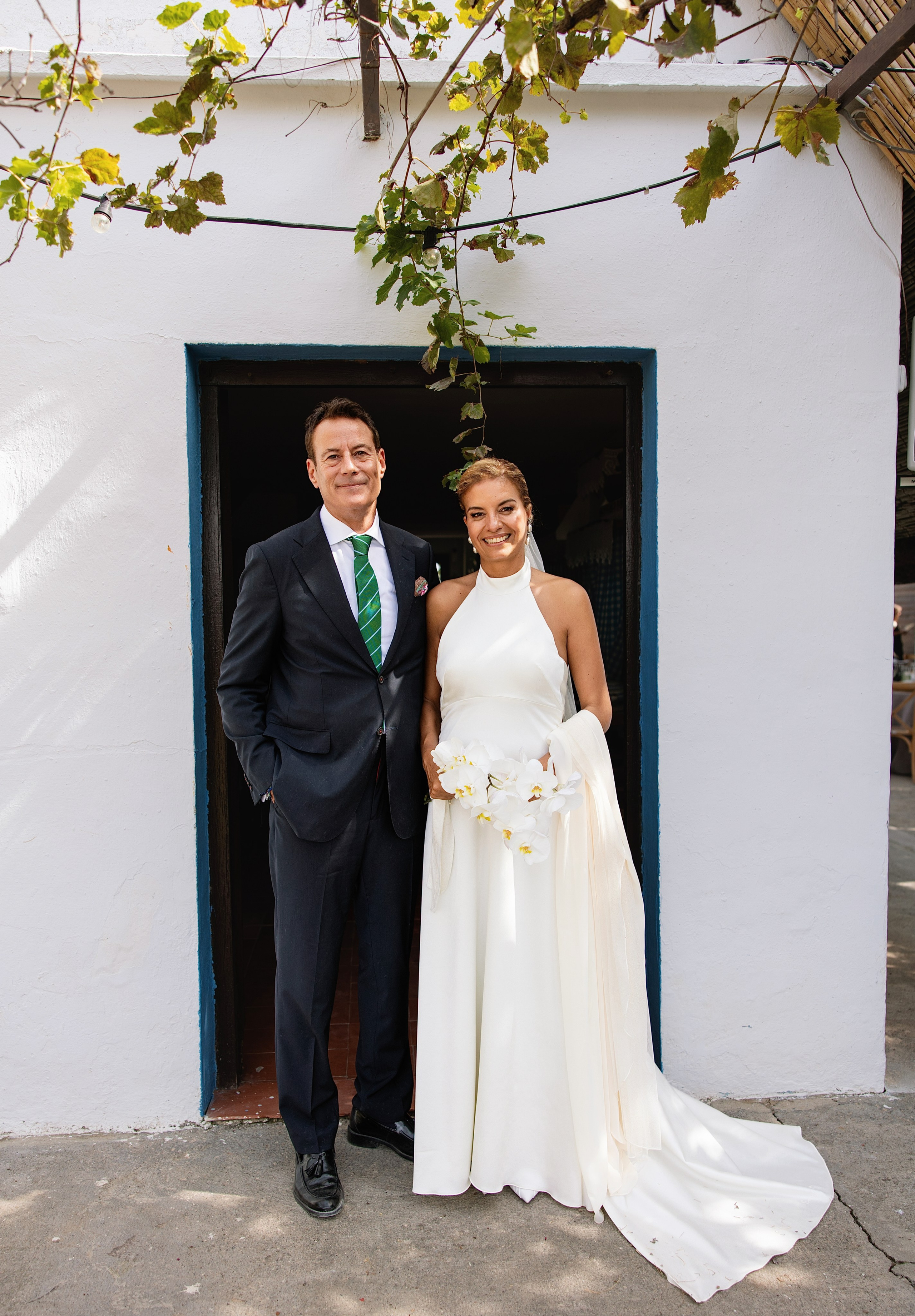 Los novios Ghislain y Miguel posando en la puerta blanca de la barraca, boda en El Palmar, Valencia