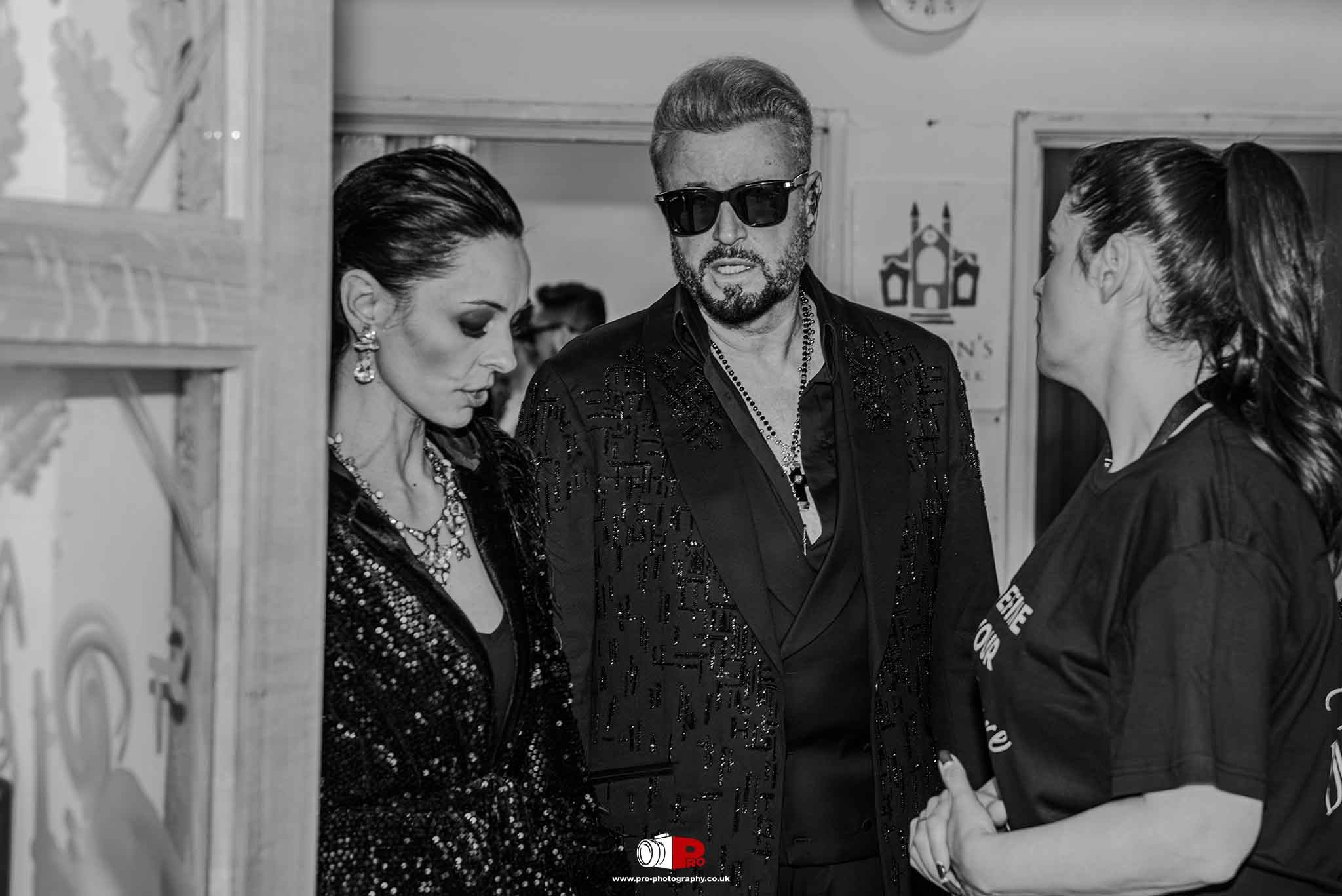 A striking black and white image of  Cosmina Pasarin, Catalin Botezatu and Andreea Hasie VIP guests in glamorous attire behind the scenes at a fashion event.
