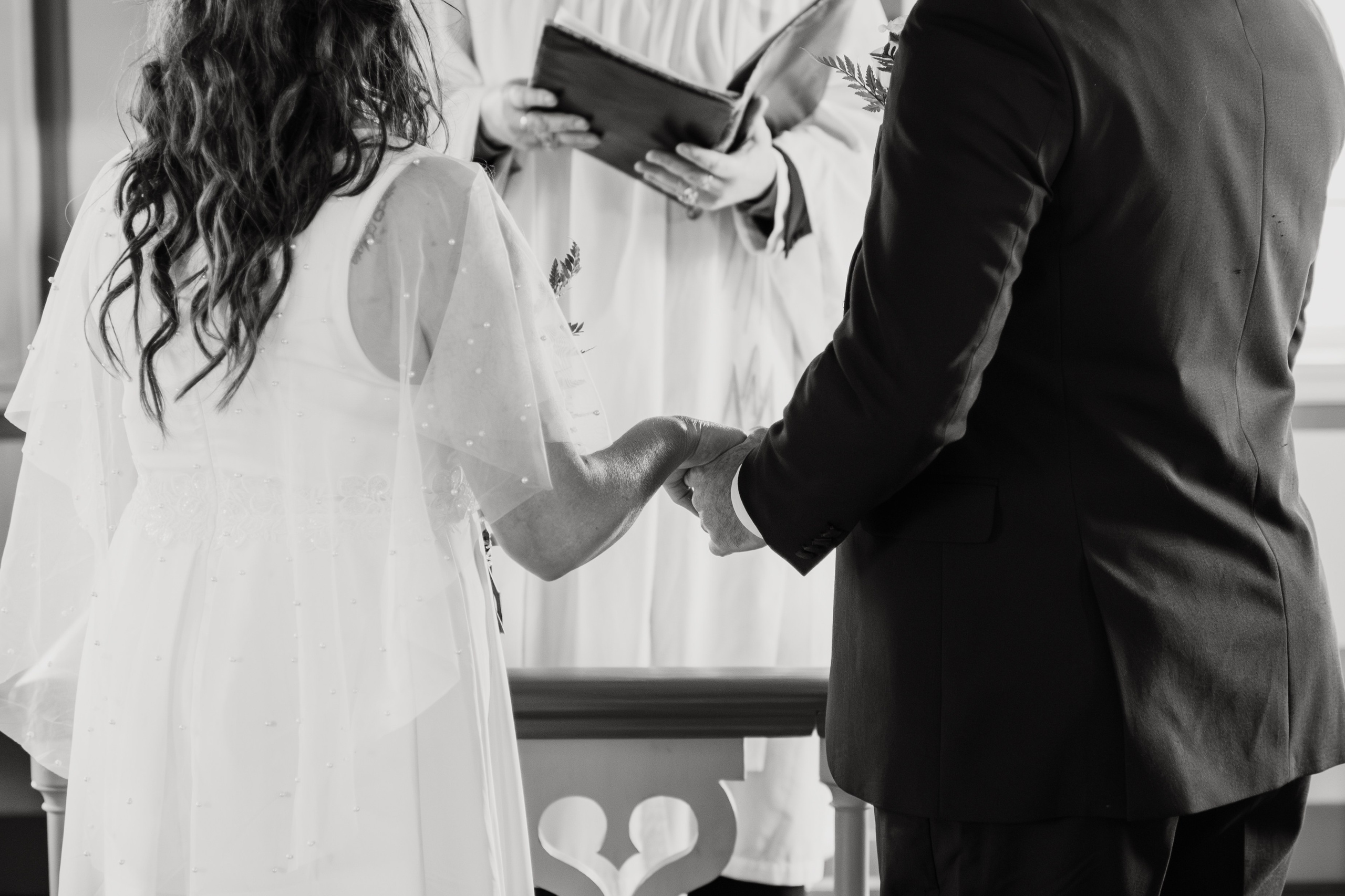 Newlyweds walking towards Búðakirkja, with the wild Icelandic coastline stretching behind them.