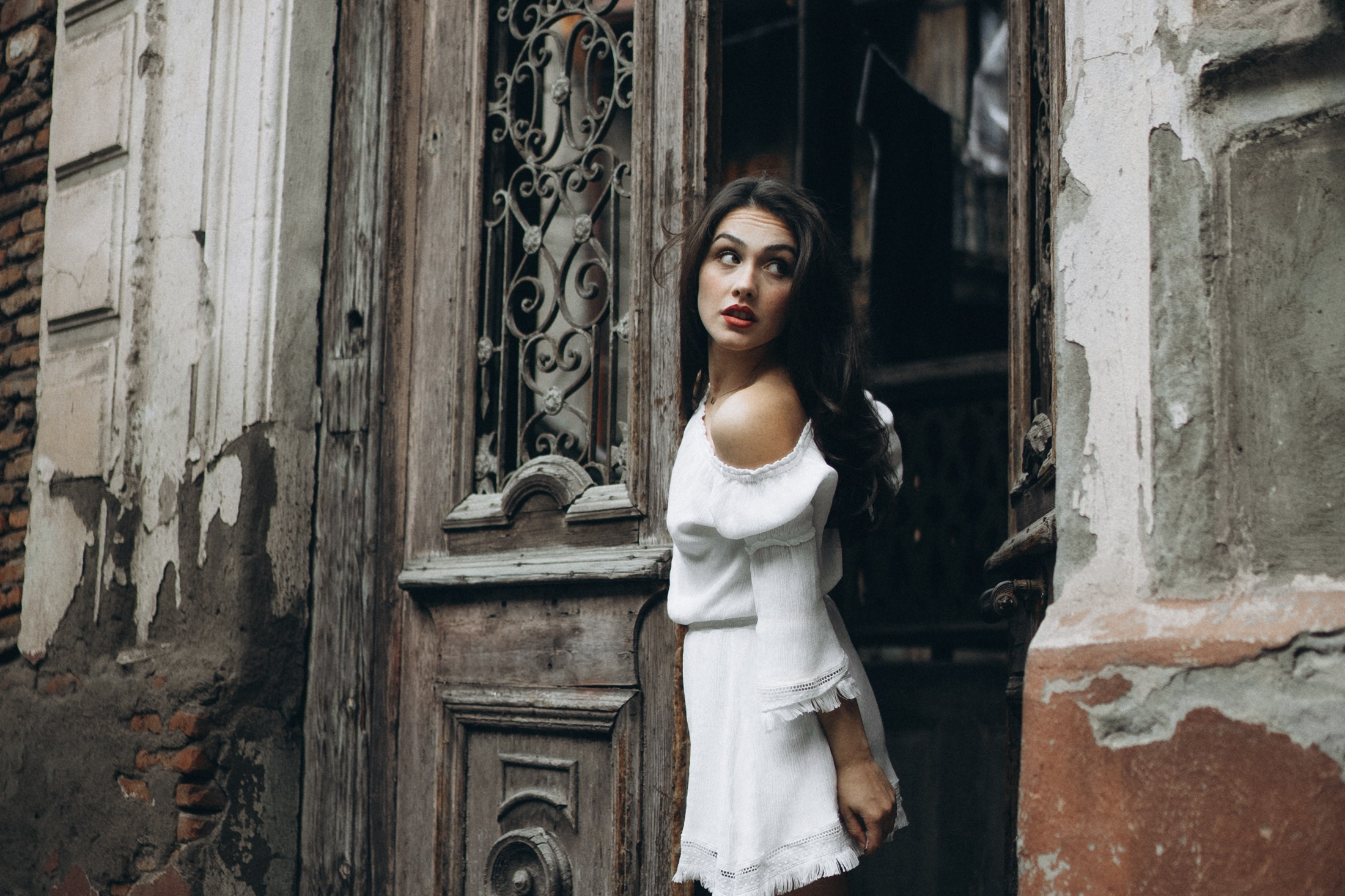 Frau im weißen Kleid steht vor alten Holztüren – künstlerische Portraitfotografie Dresden