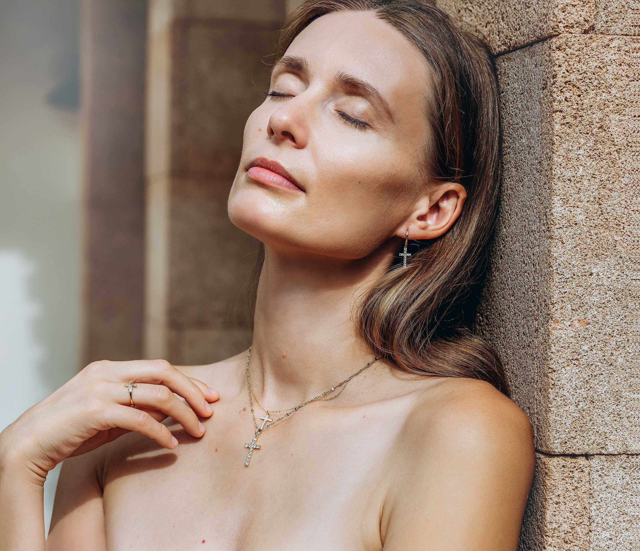 Elegant woman with closed eyes showcasing minimalist cross jewelry in a refined indoor brand photoshoot taken in Valencia, Spain — ideal for brands seeking high-end product photography, lifestyle content, and visual branding services across Spain.