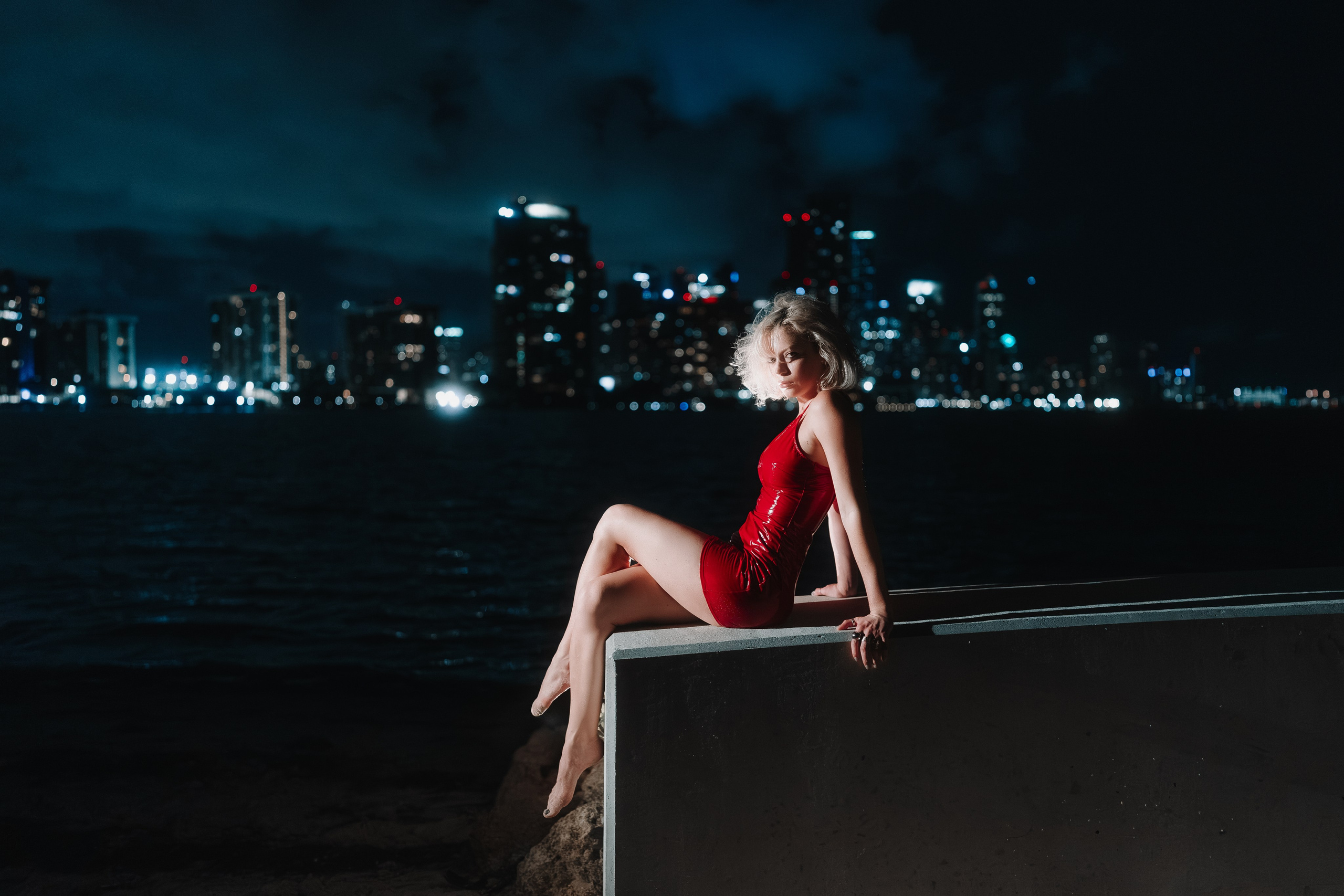 The distant city and calm shoreline create emotional contrast. Miami nighttime aesthetic.