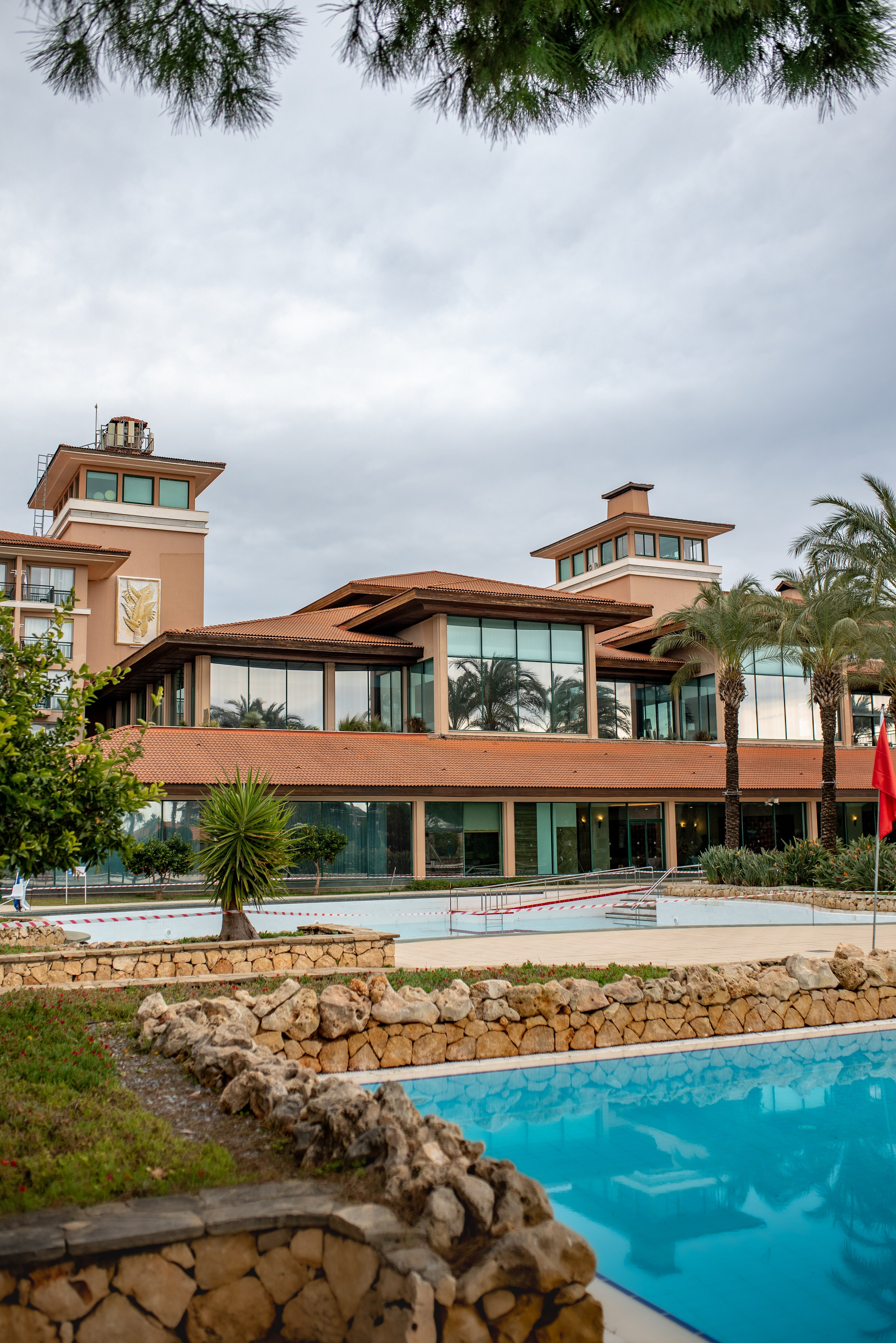 IC Hotels family resort in Antalya surrounded by palm trees and gardens, professional hotel photographyDescriptionProfessional hotel photography of IC Hotels family resort in Antalya, showcasing the main buildings and green landscape, in Antalya photographed by professional hotel photographer