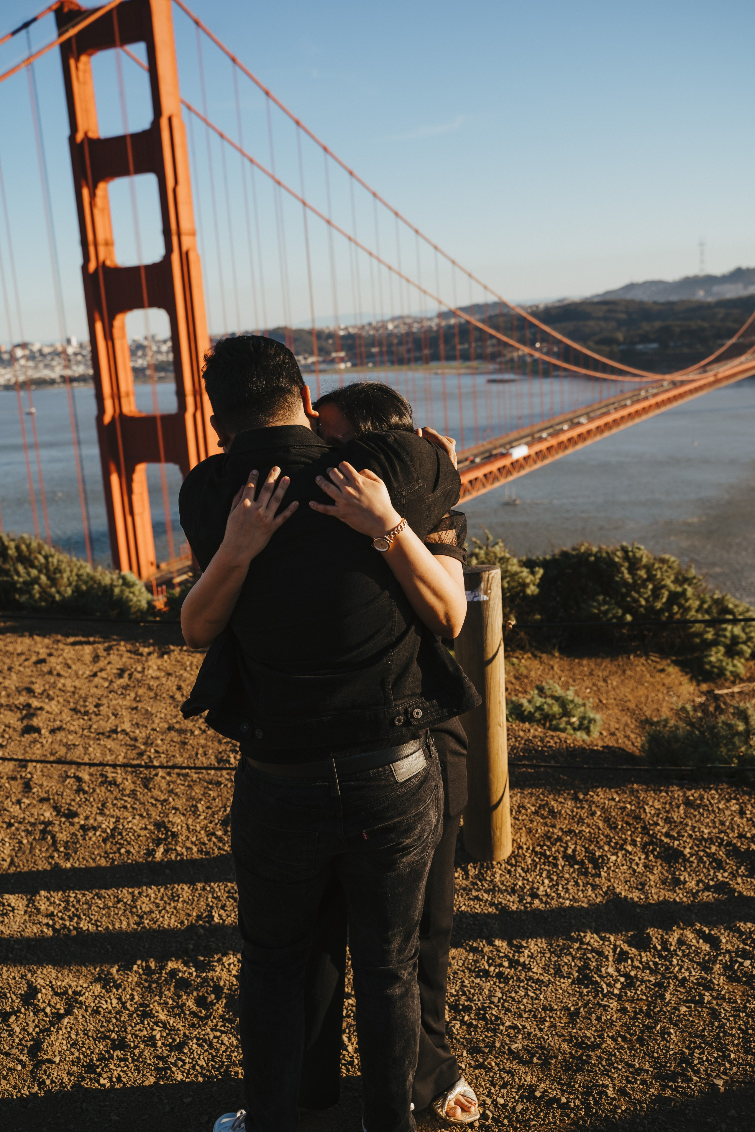 Proposal.  Overlooking the golden San Franisco Bridge sunset with a couple. Photographer Video. 