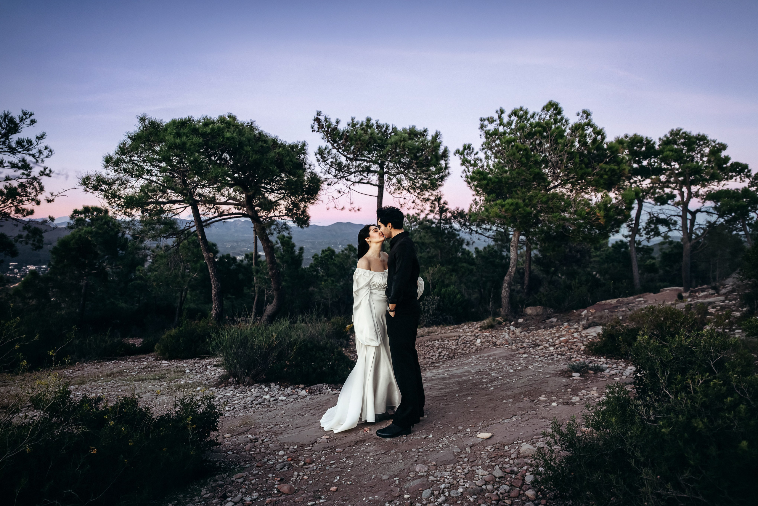 Bride and groom standing together on a mountain path at dusk during a destination elopement in Barcelona, Spain. This cinematic wedding portrait captures the serenity and intimacy of a small outdoor ceremony.