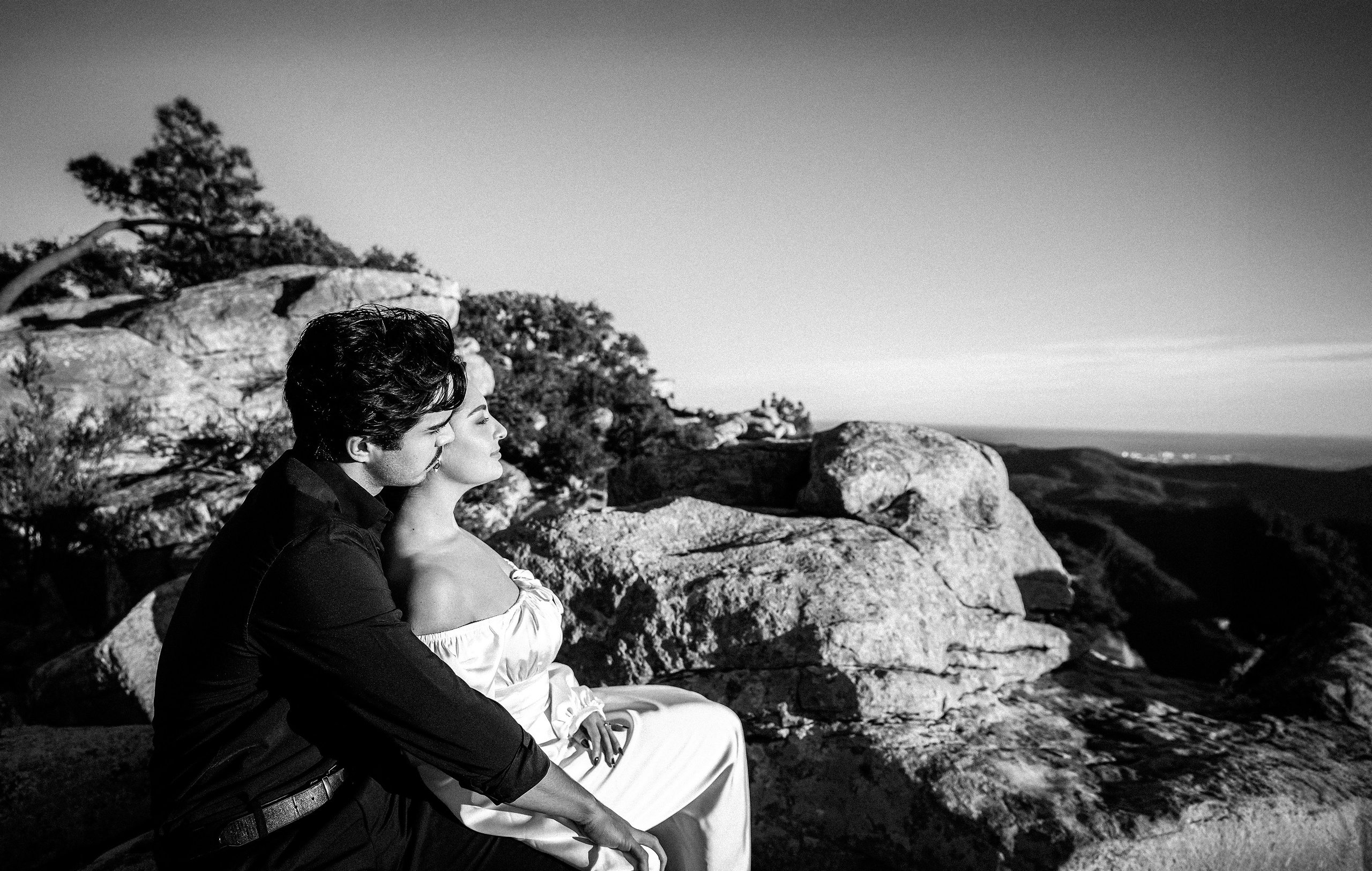 Engagement photoshoot in València, Spain, featuring a couple seated together on rocky cliffs in a timeless black-and-white composition, capturing a quiet, intimate wedding love story moment surrounded by natural landscapes — ideal for engagement photography, pre-wedding sessions, elopements, and professional engagement and wedding photoshoots in València and across Spain.