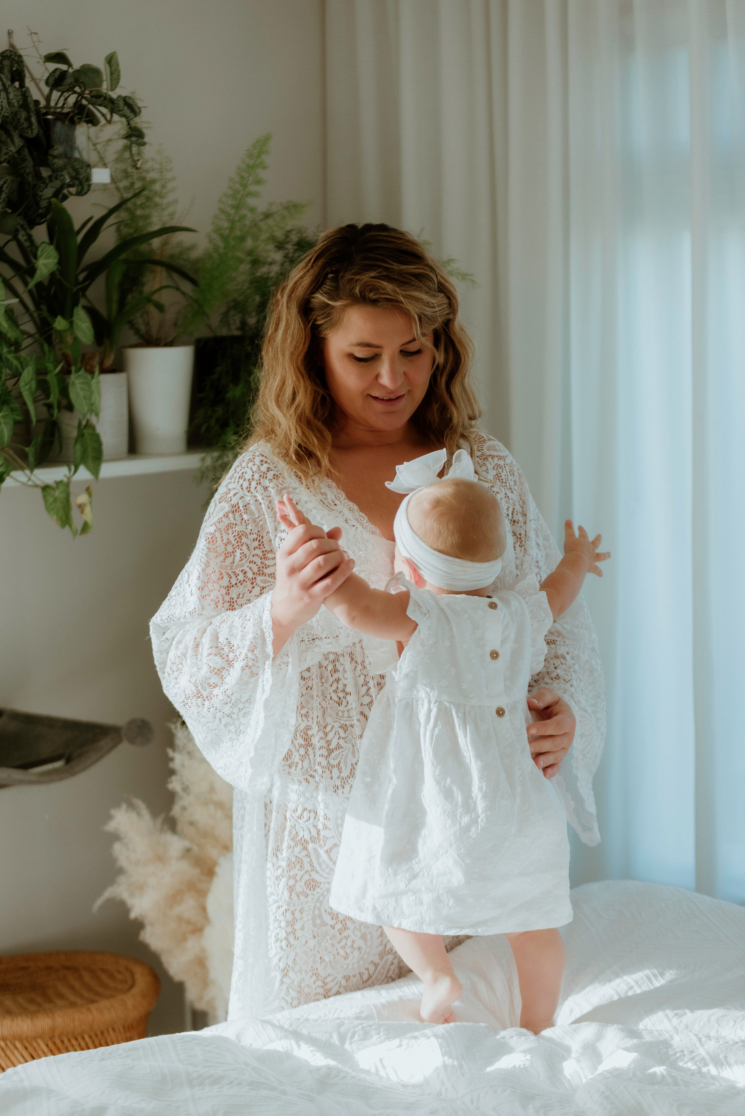 An enchanting outdoor maternity photoshoot at the client's house. The image features a radiant mother and her daughter, both elegantly dressed in white, against the backdrop of their home. The simplicity of their attire and the natural surroundings creates a timeless and intimate atmosphere. Book a personalized outdoor session with MD Studio to capture beautiful moments in the comfort of your own home