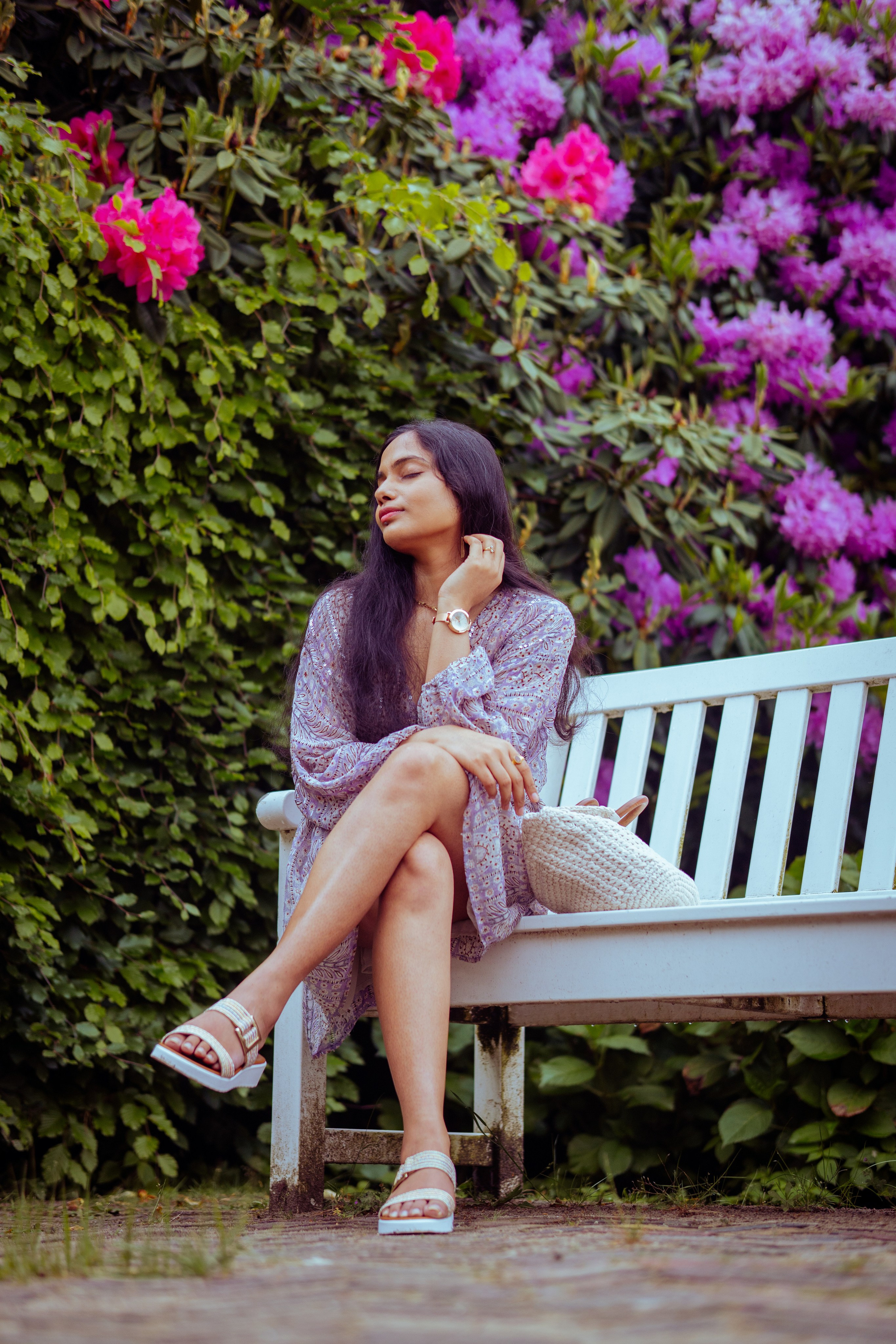 woman sitting on a white bench with flowers as background