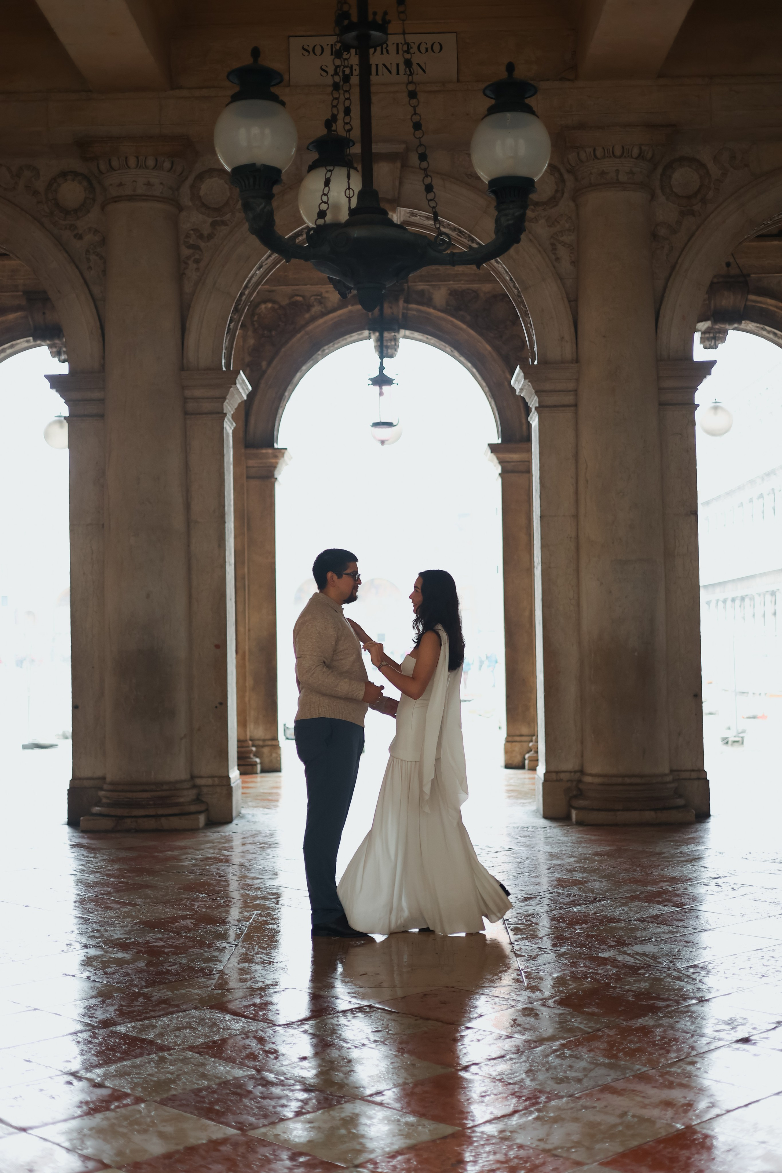 Romantic rainy-day couple photo in Venice, showcasing wet cobblestone streets, reflections, and intimate moments