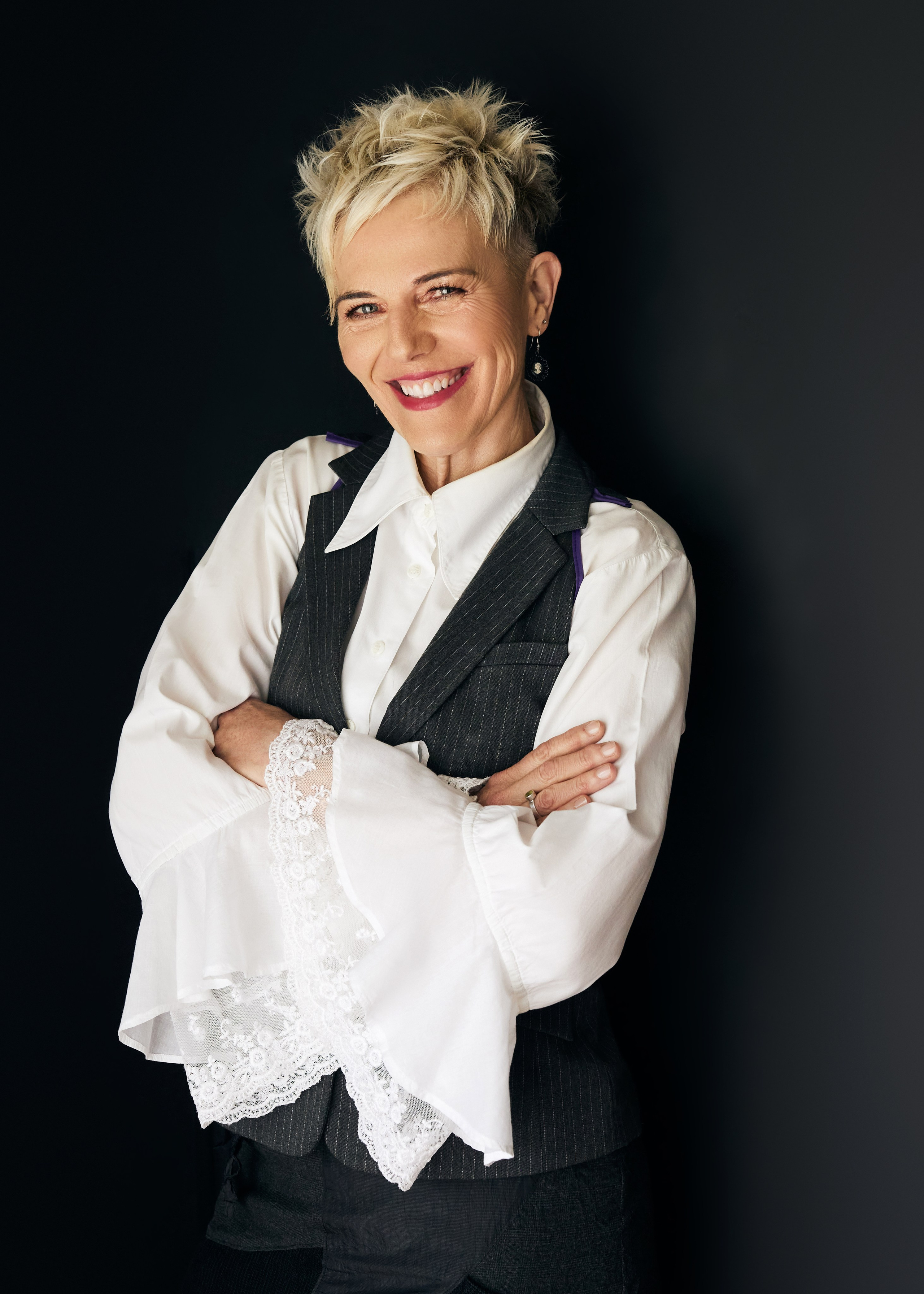 mature woman with short pixie hair cut, wearing ruffled white shirt 