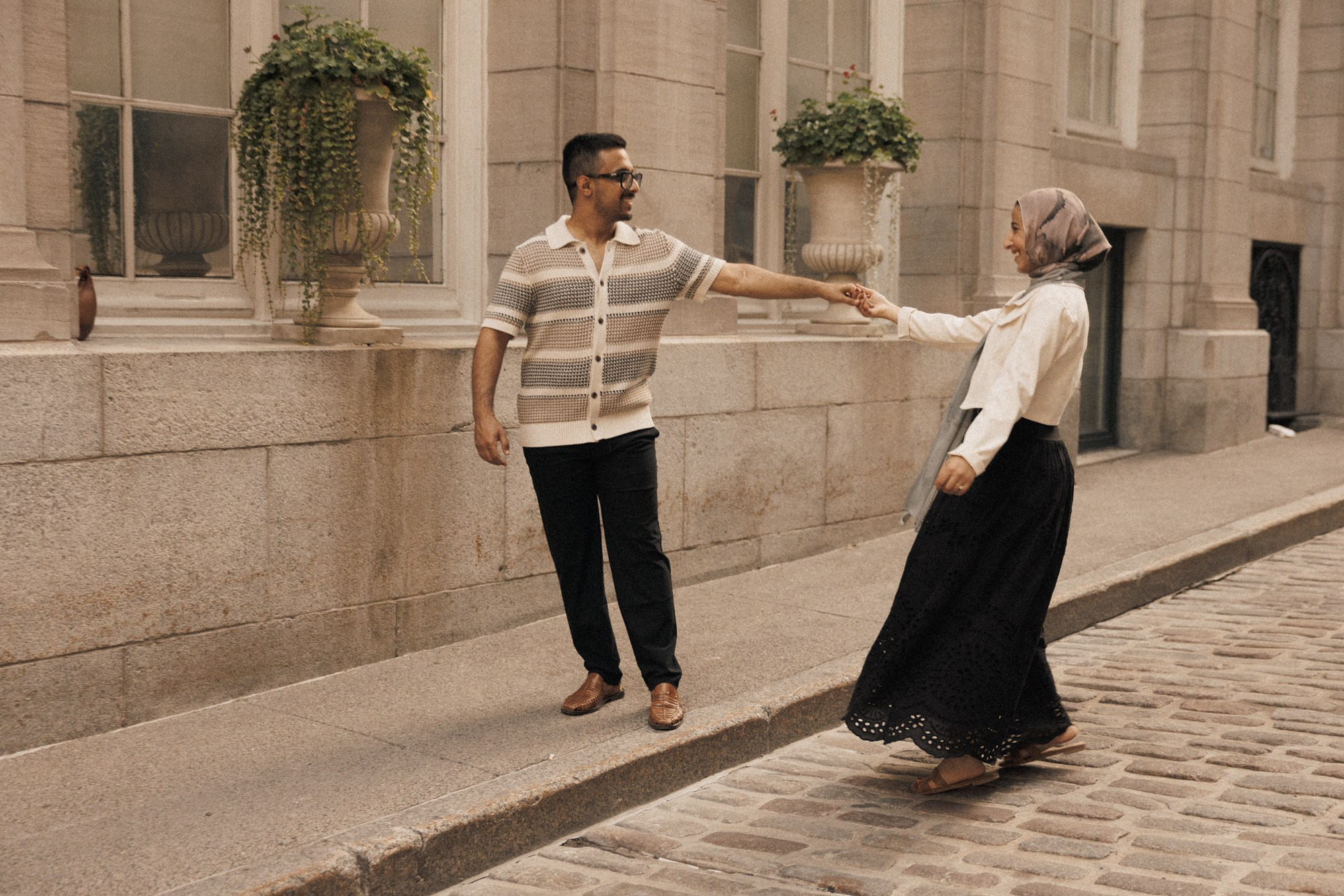 Couple holding hands on cobblestone street in Montreal
